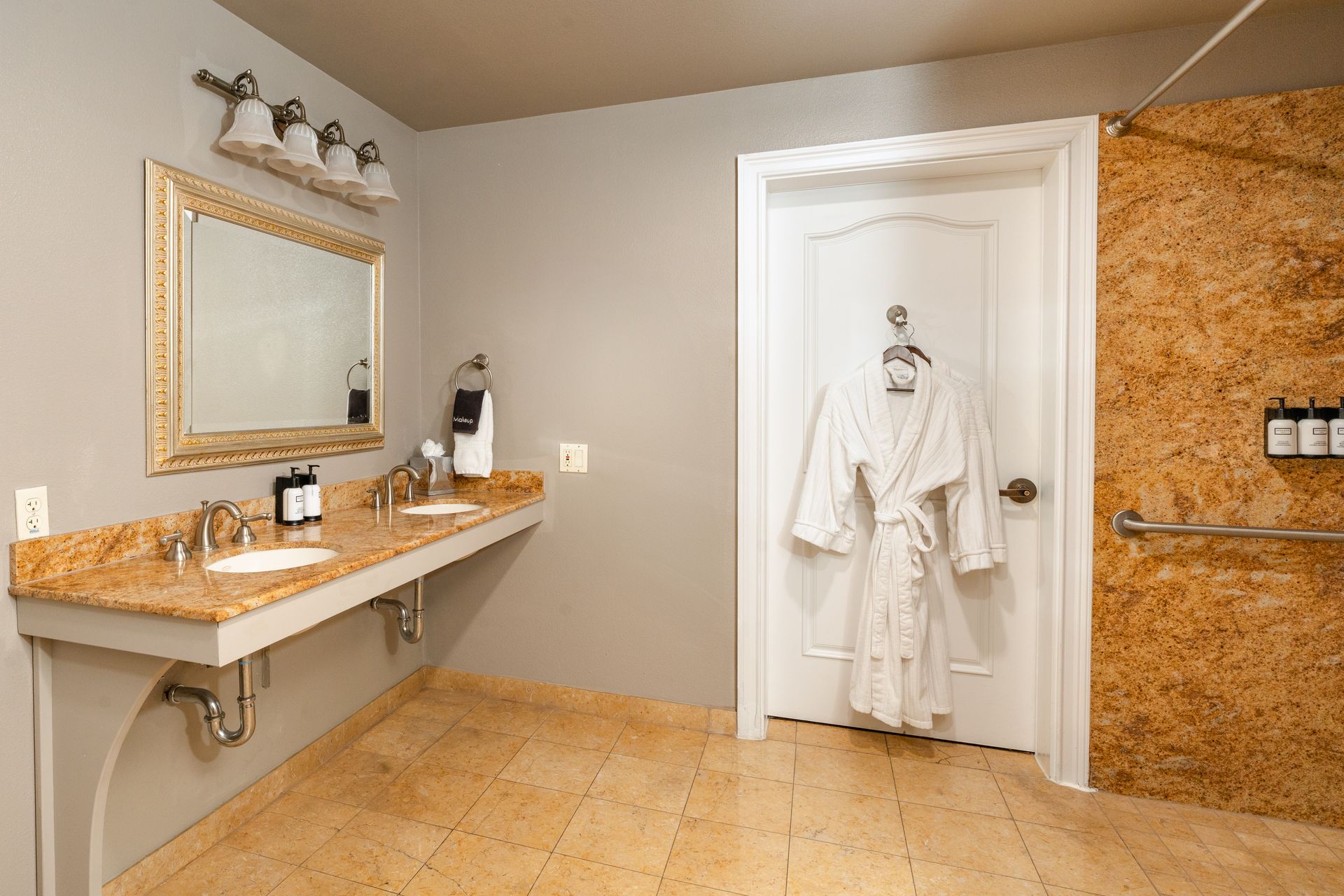 Bathroom with accessible sink, textured wall, robe hanging on door, and shower.