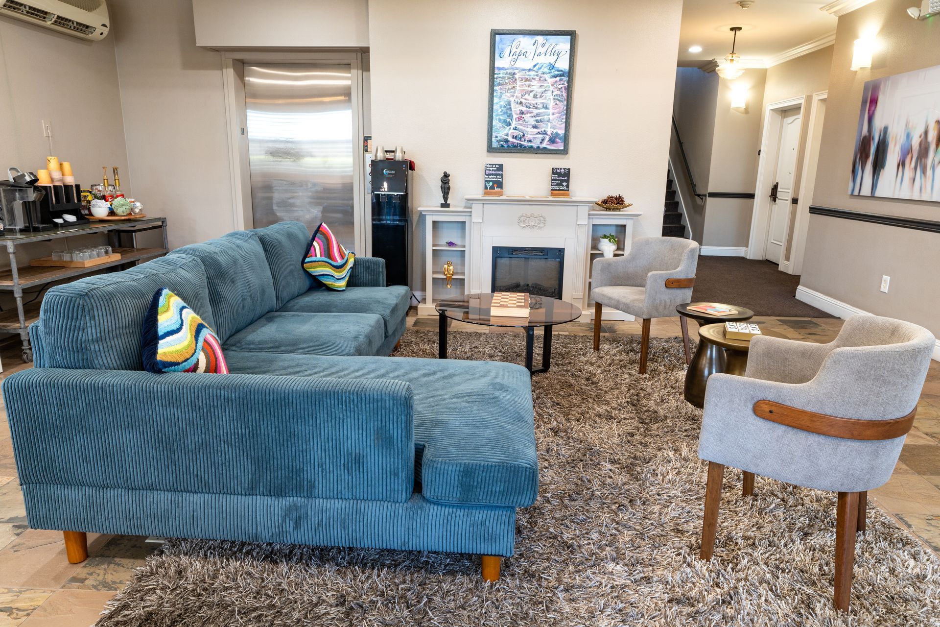 Lounge area with teal sectional sofa, two armchairs, a fireplace, and coffee table on a shag rug.