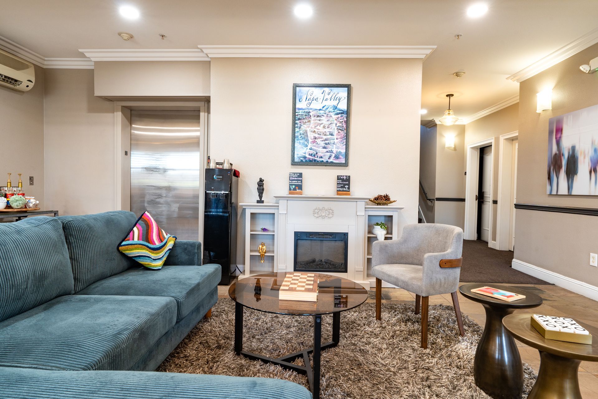 Living room with turquoise couch, fireplace, artwork, and various furnishings.