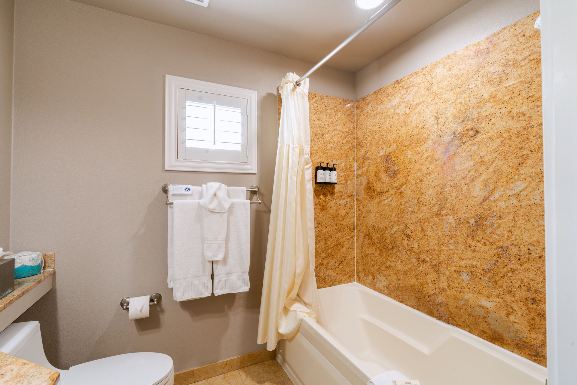 Bathroom with a tub, beige walls, a small window, and a shower curtain.