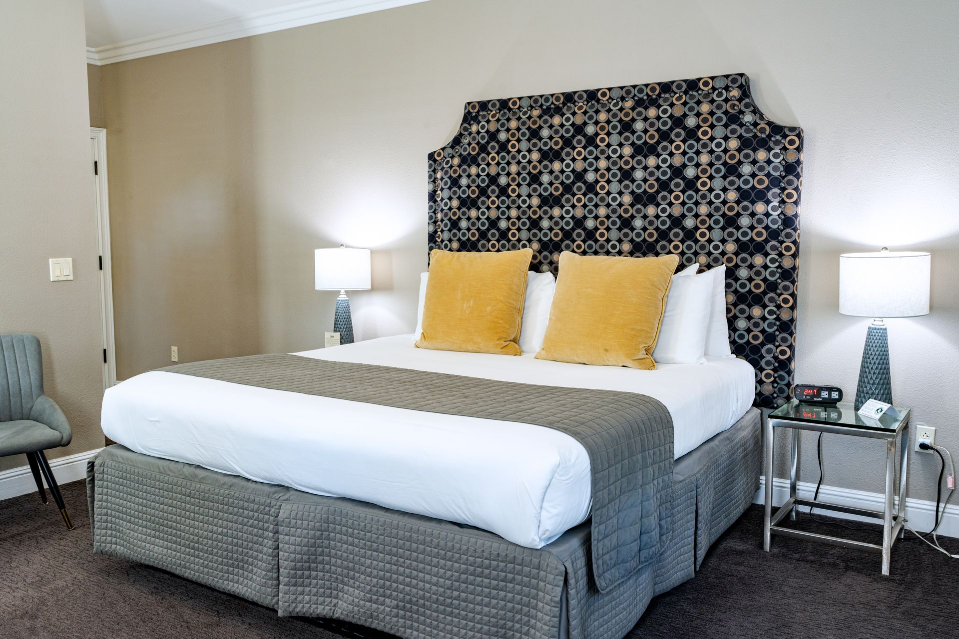 Bedroom with a large bed, decorative headboard, yellow pillows, and bedside lamps.