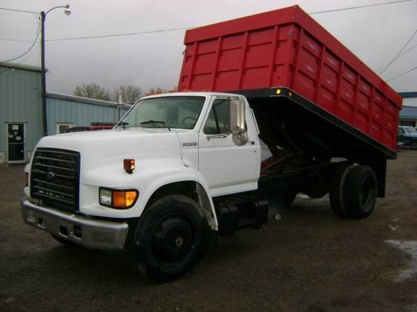 A White Dump Truck with A Red Bed Is Parked in A Parking Lot
