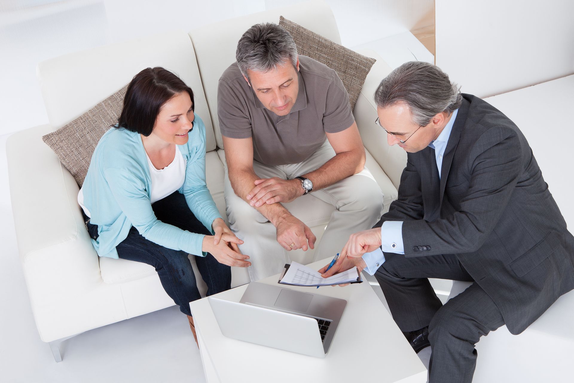 A man and woman are sitting on a couch looking at a laptop