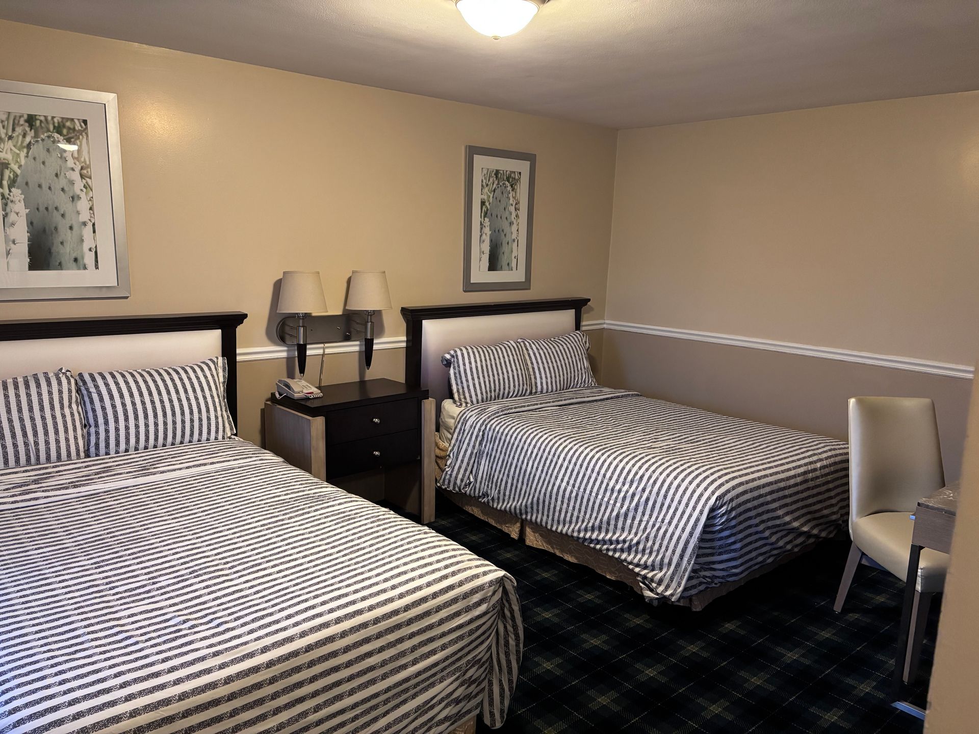 A hotel room with two beds and a large window.