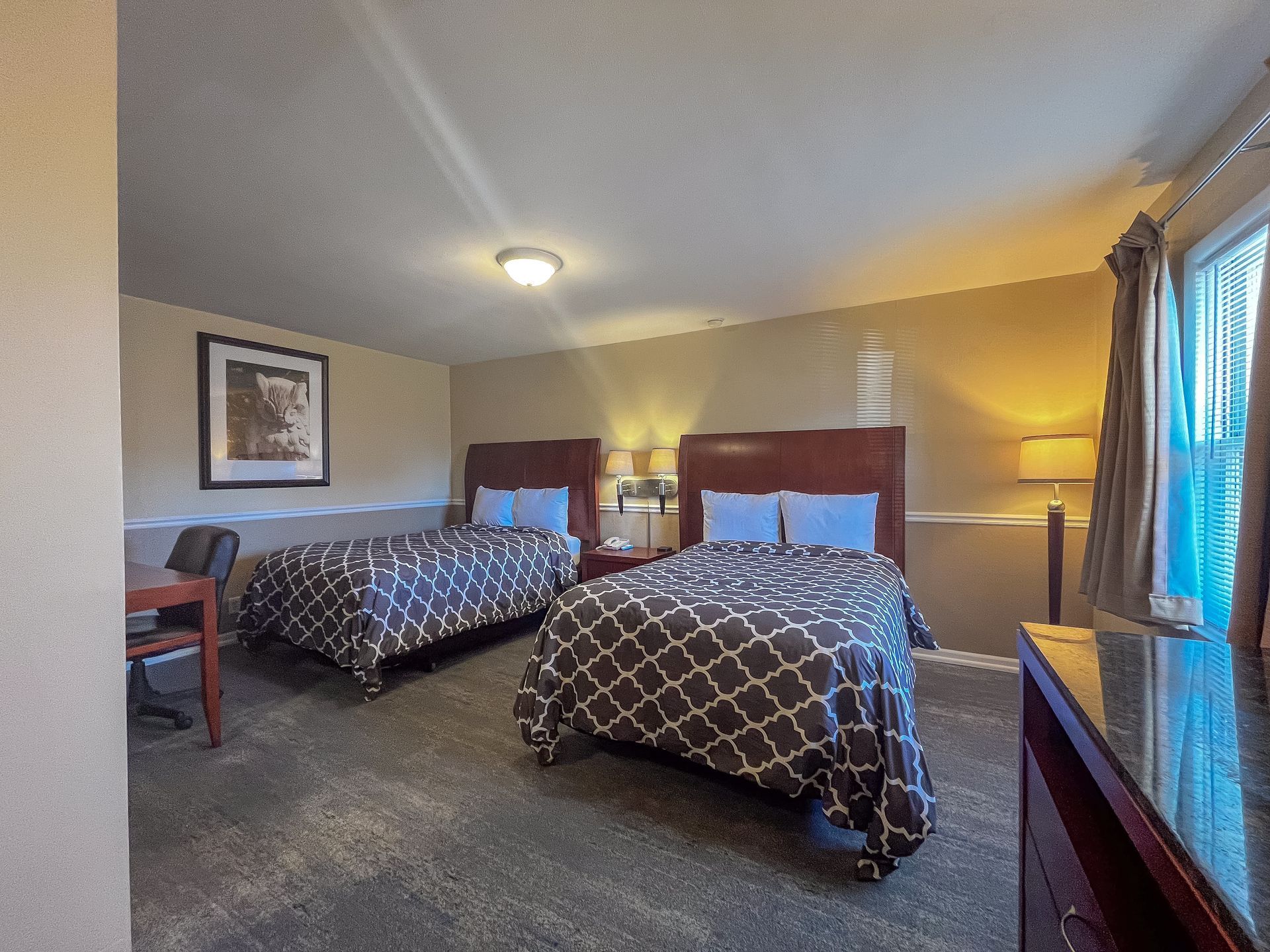A hotel room with a bed, couch, table and window.