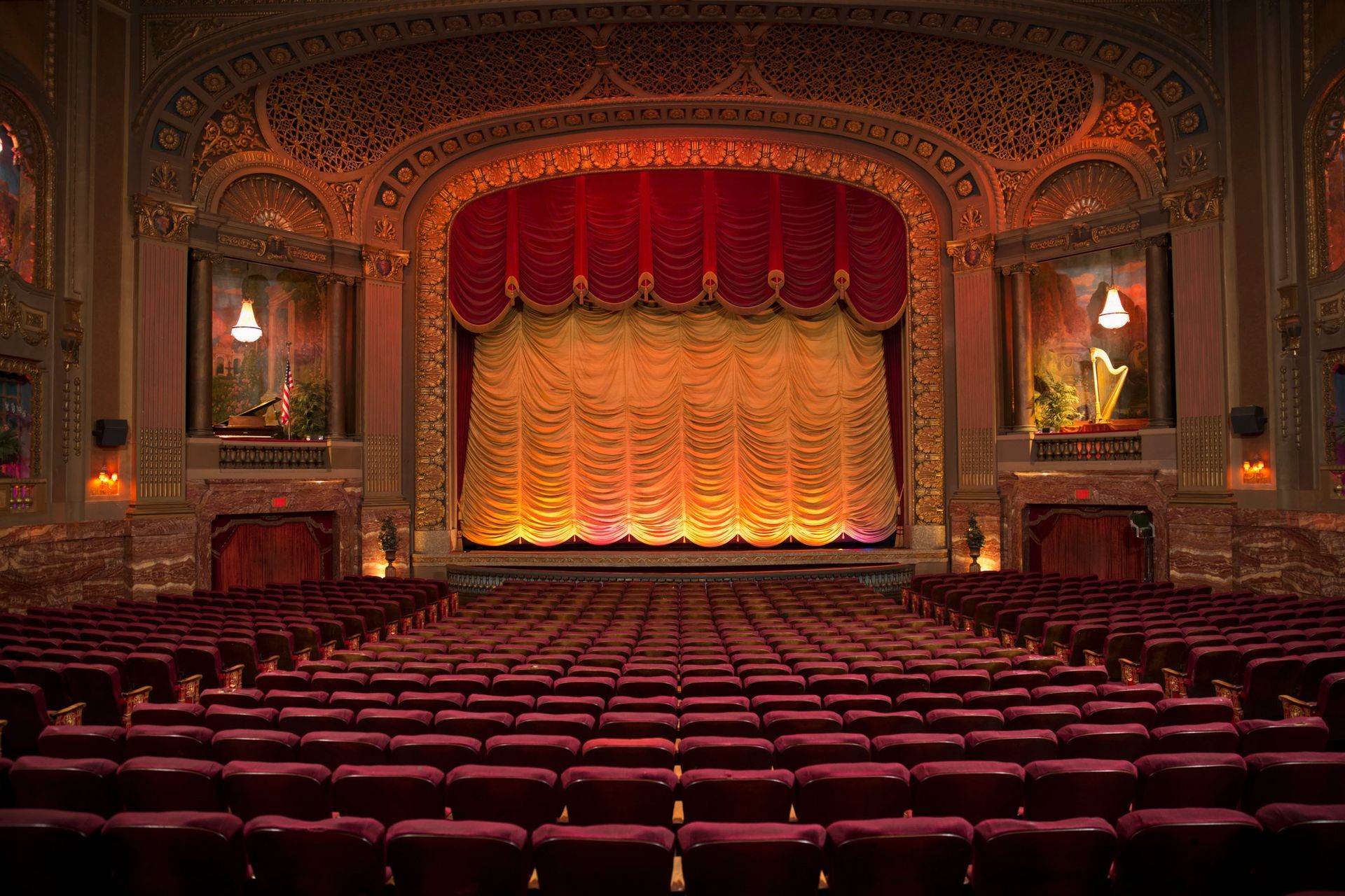 An empty theater with rows of red seats and a stage.
