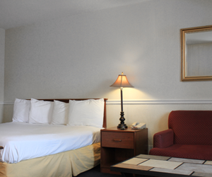 A hotel room with a large bed and a lamp.