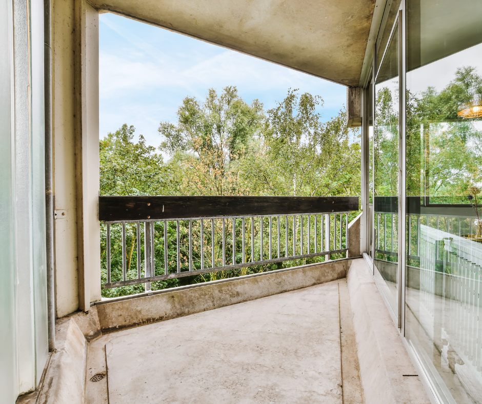 An empty balcony with a railing and trees in the background