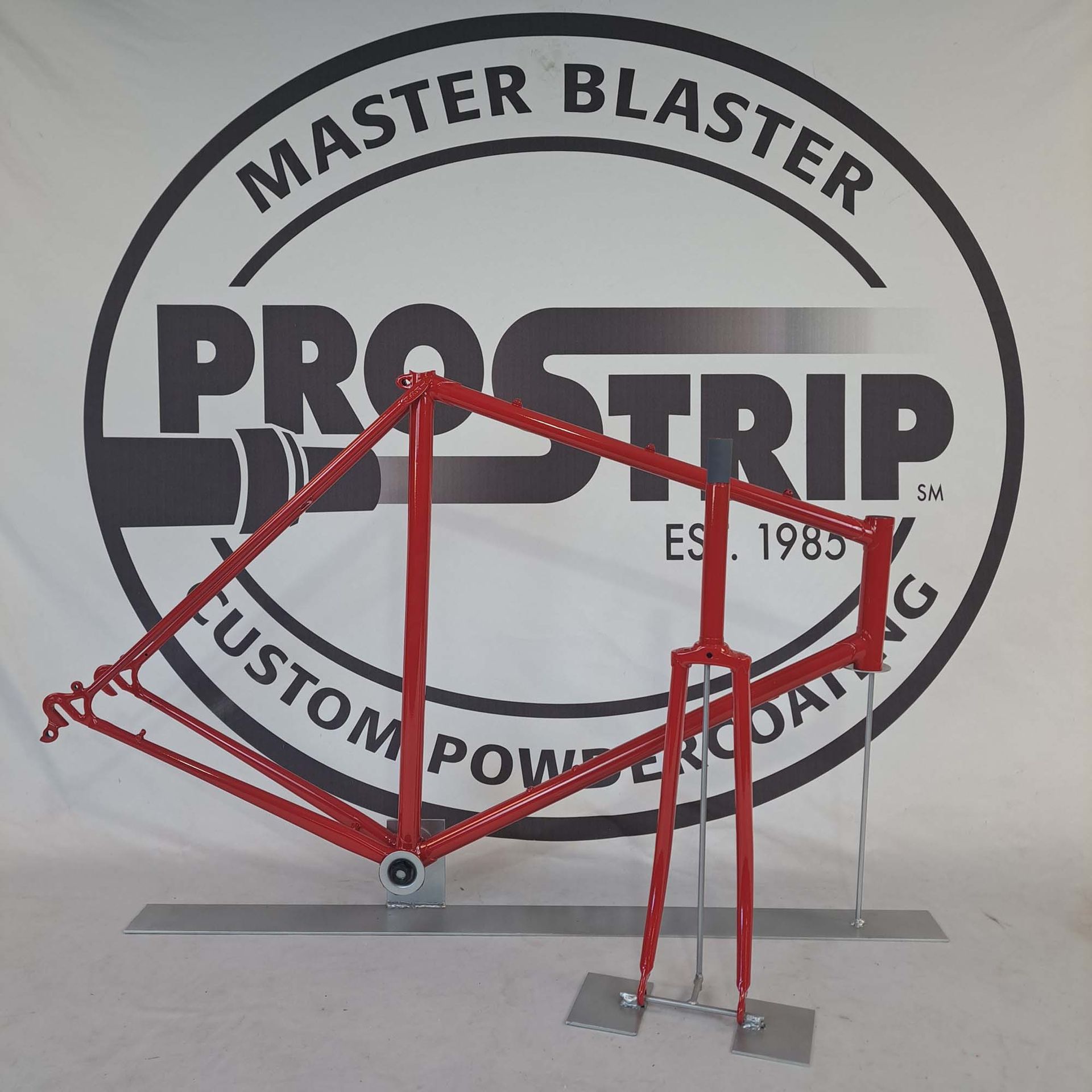 A red bicycle frame in front of a master blaster logo