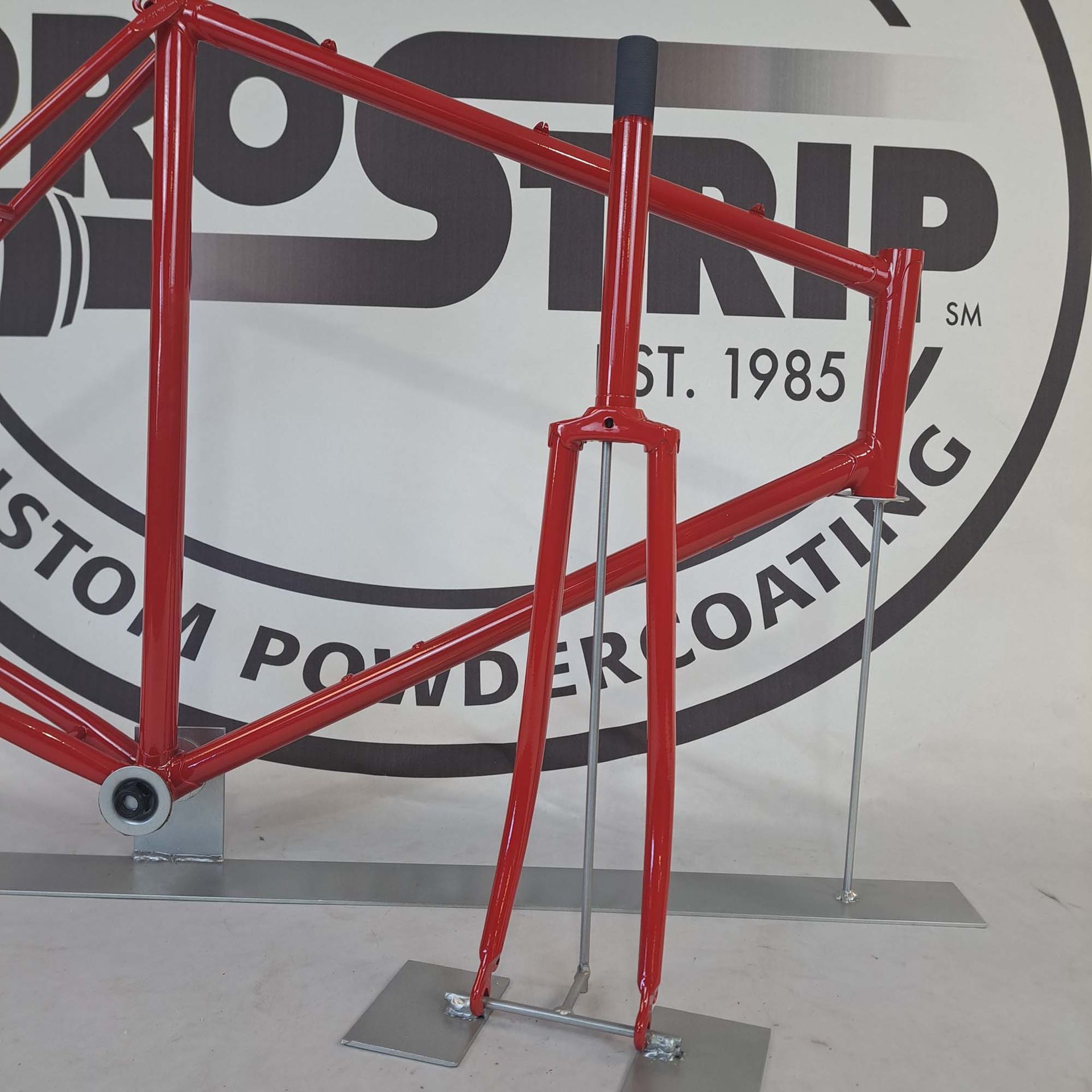 A red bicycle frame is sitting in front of a pro strip logo