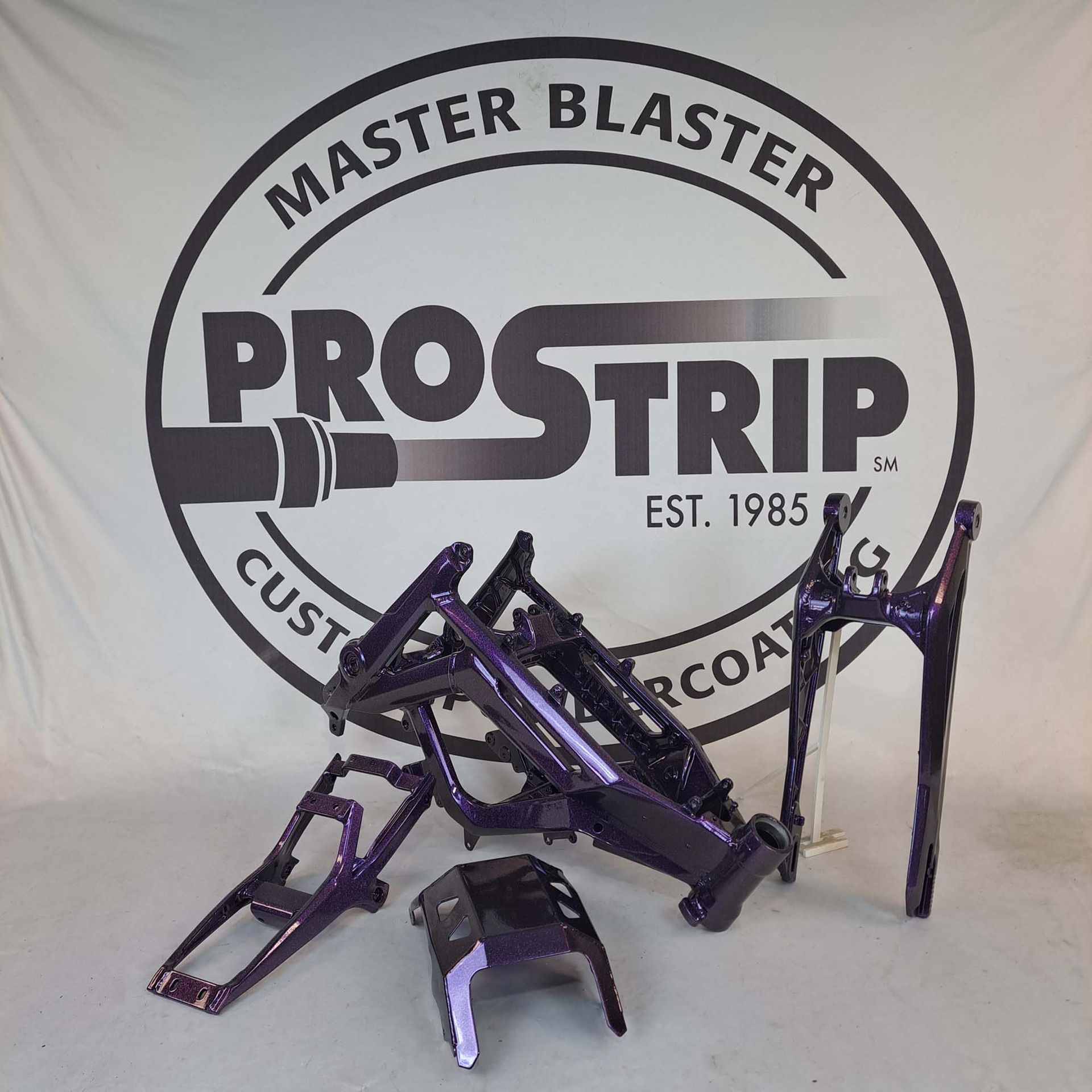 Purple motorcycle frames in front of a master blaster prostrip logo