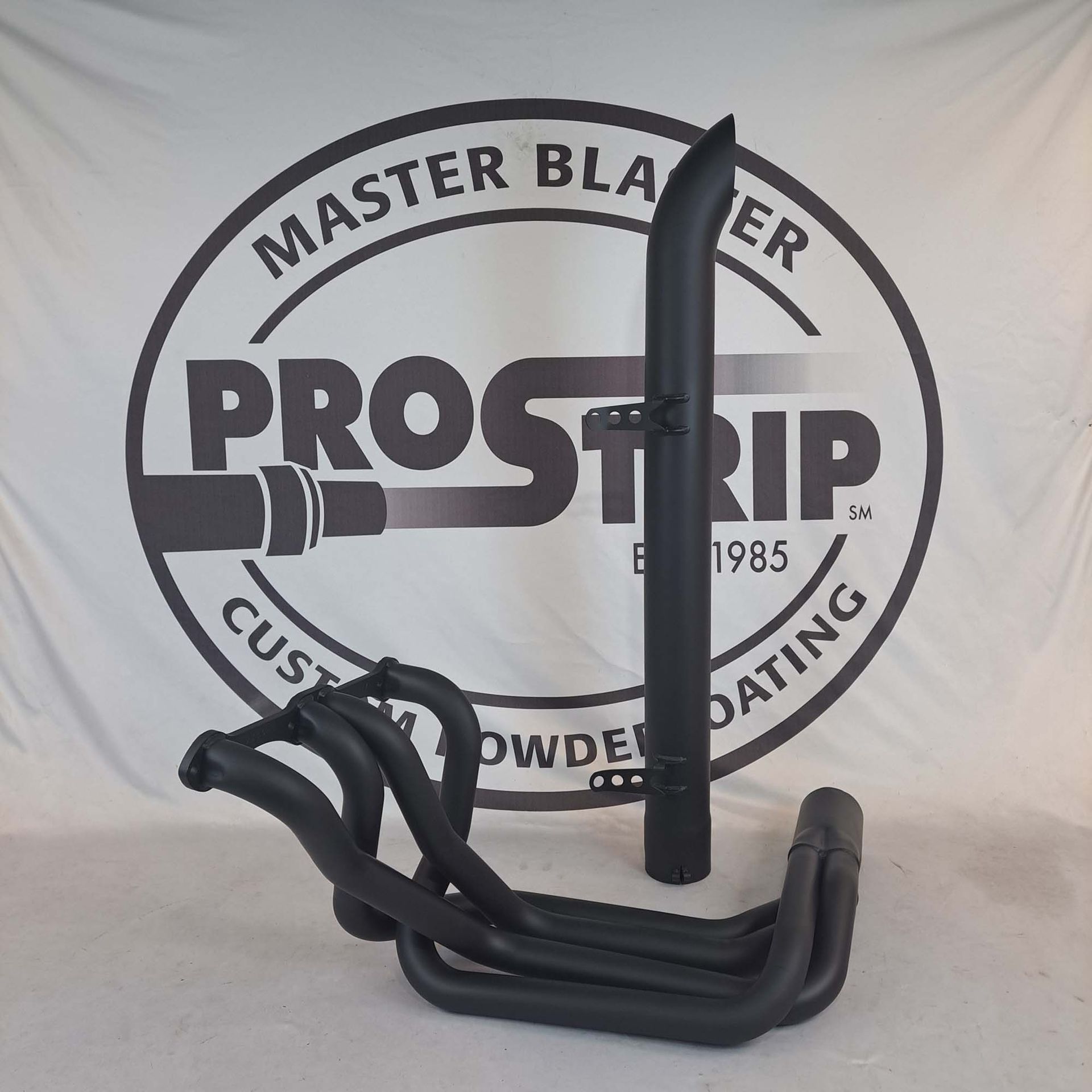 A black pipe is sitting in front of a master blaster logo