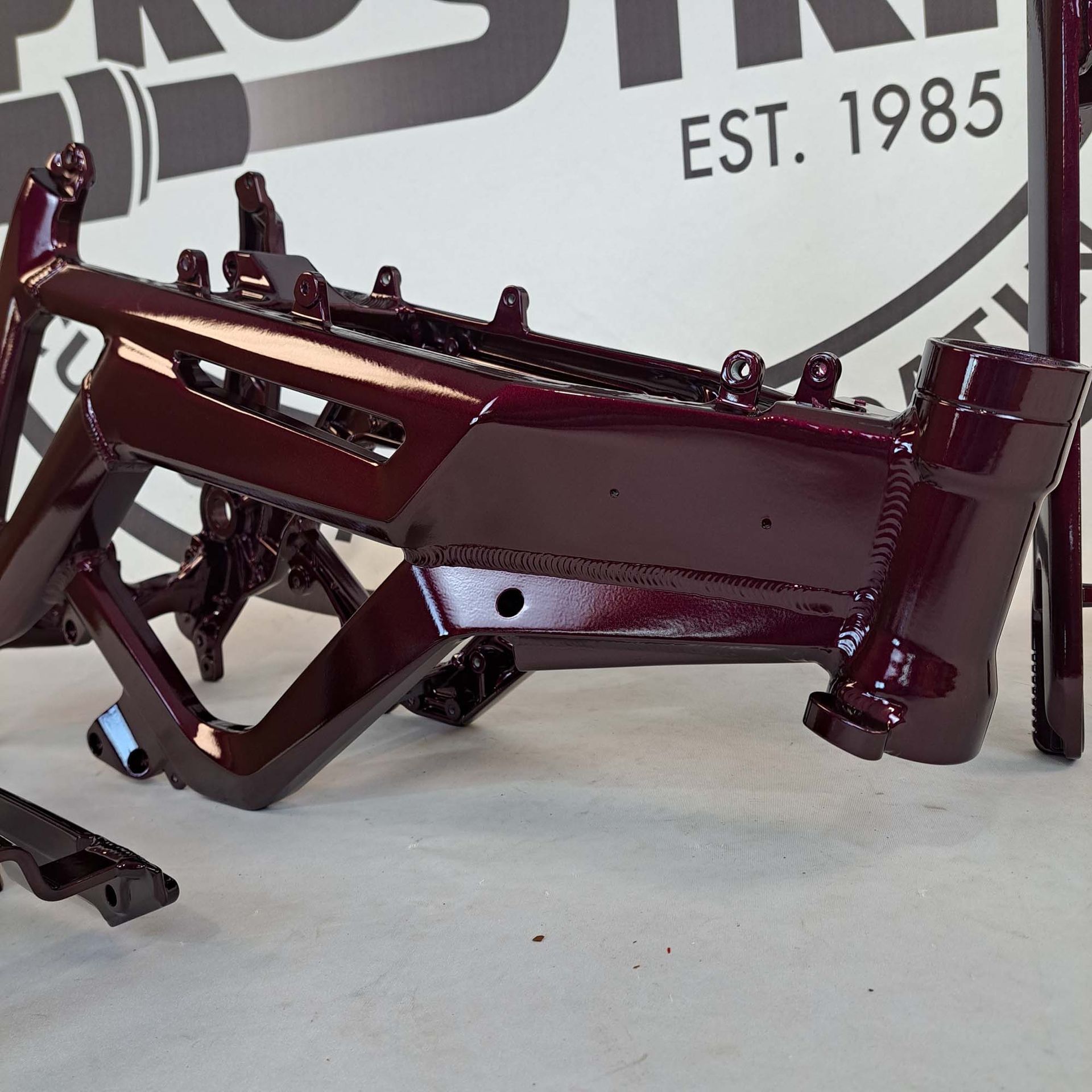 A purple motorcycle frame sits in front of a 1985 sign