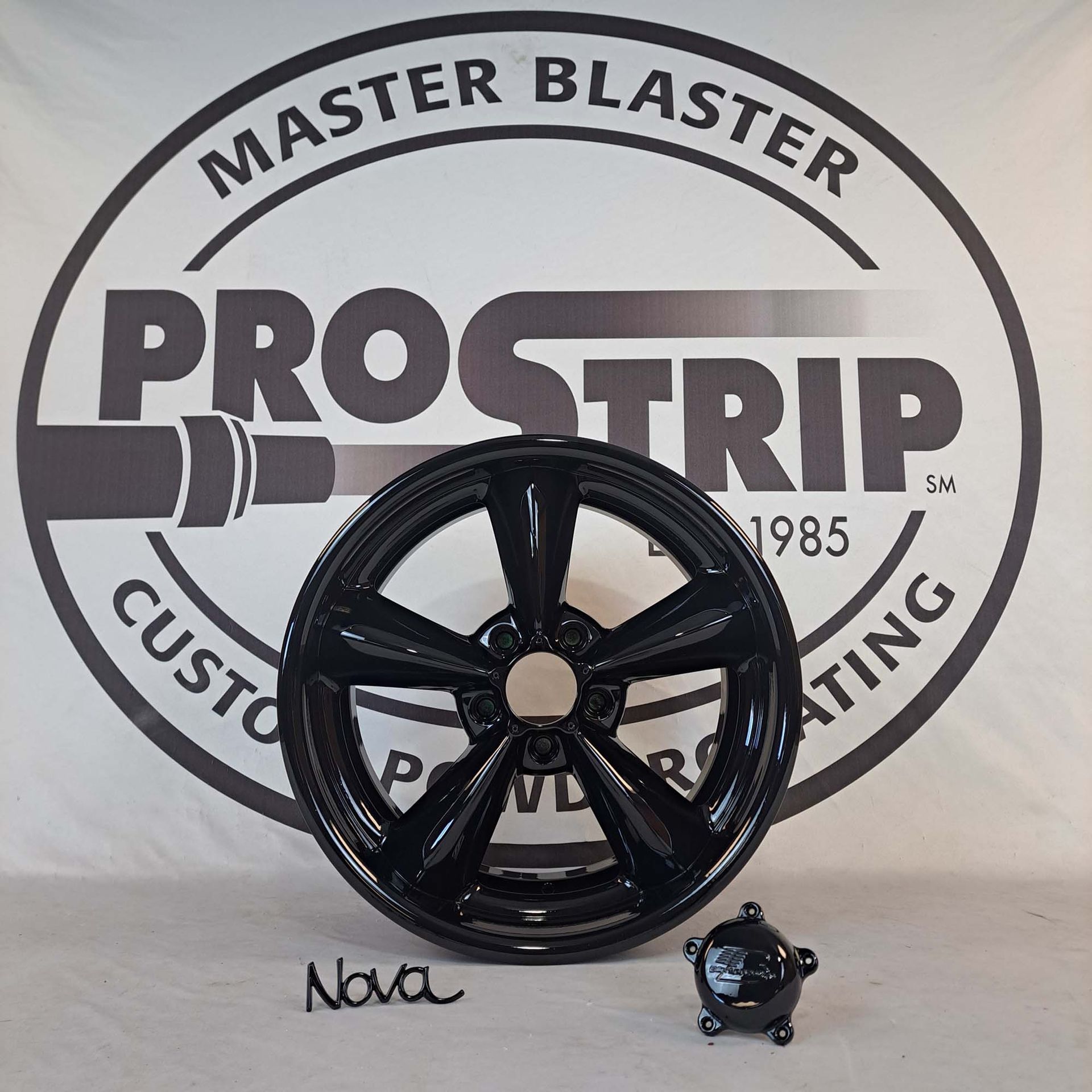 A black wheel sits in front of a master blaster logo