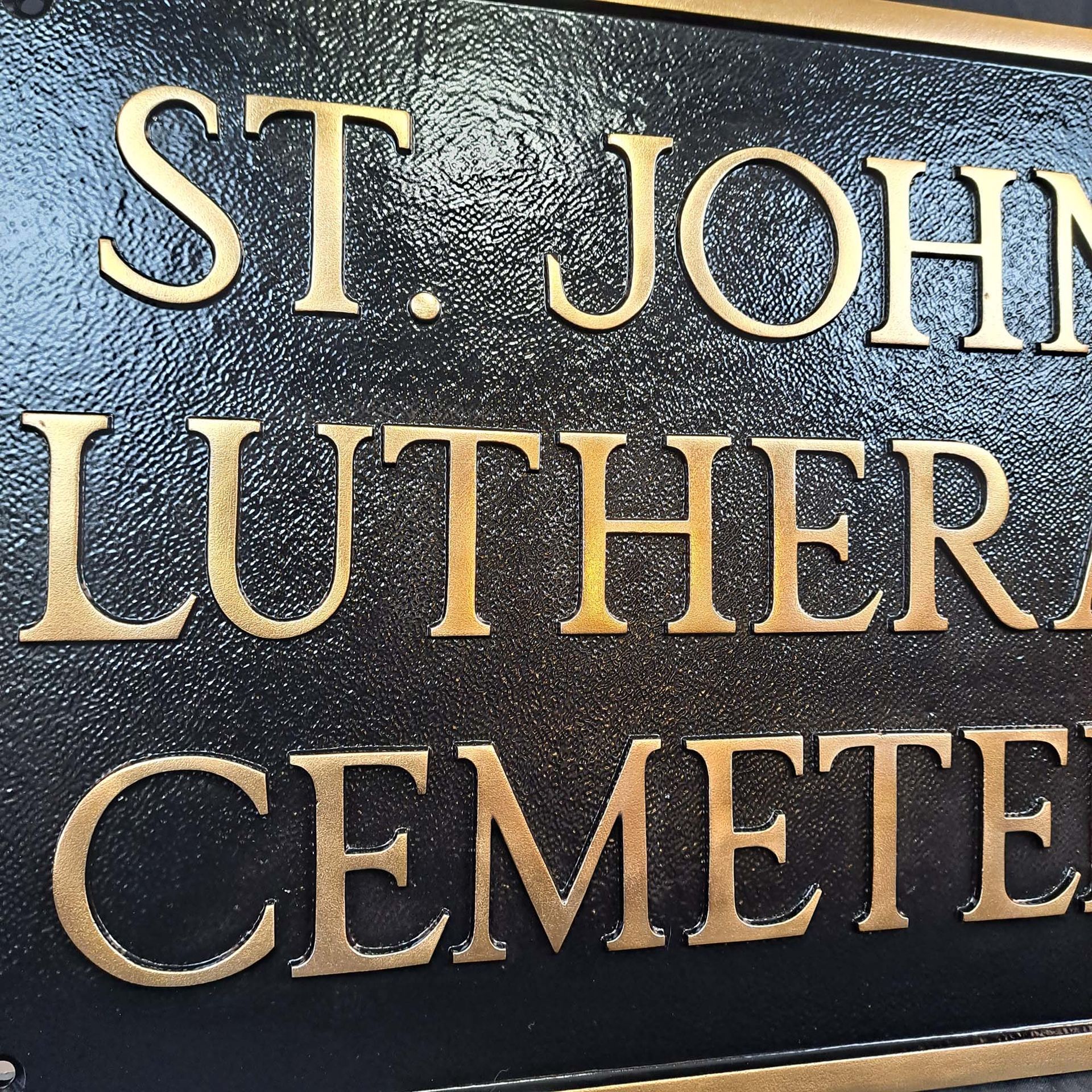 A black and gold sign that says st. john luther cemetery