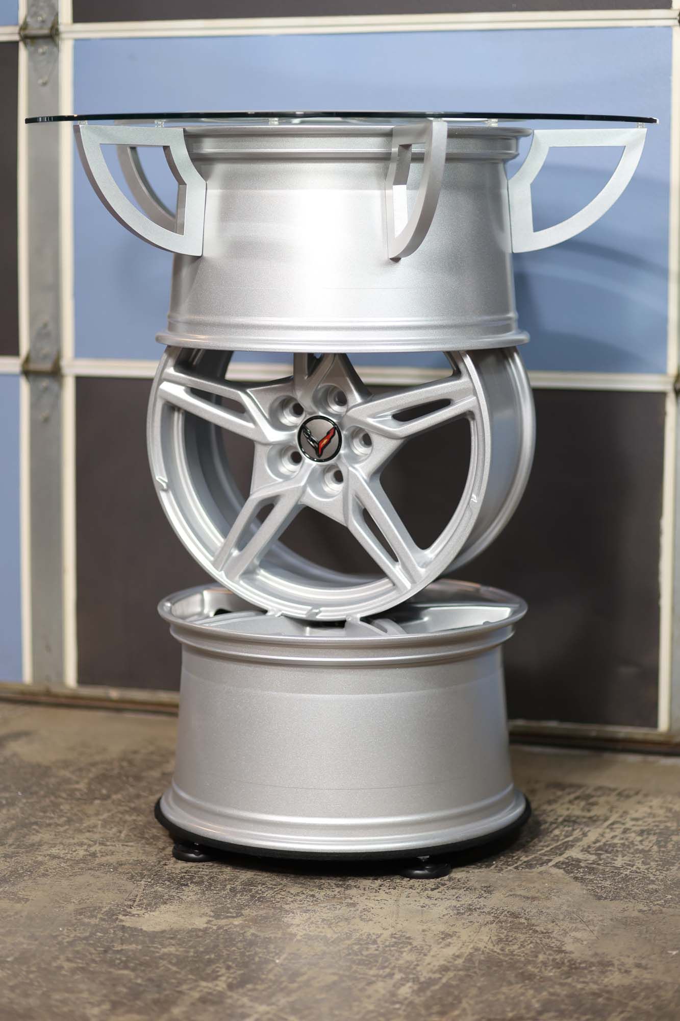 A table made out of car wheels with a glass top.