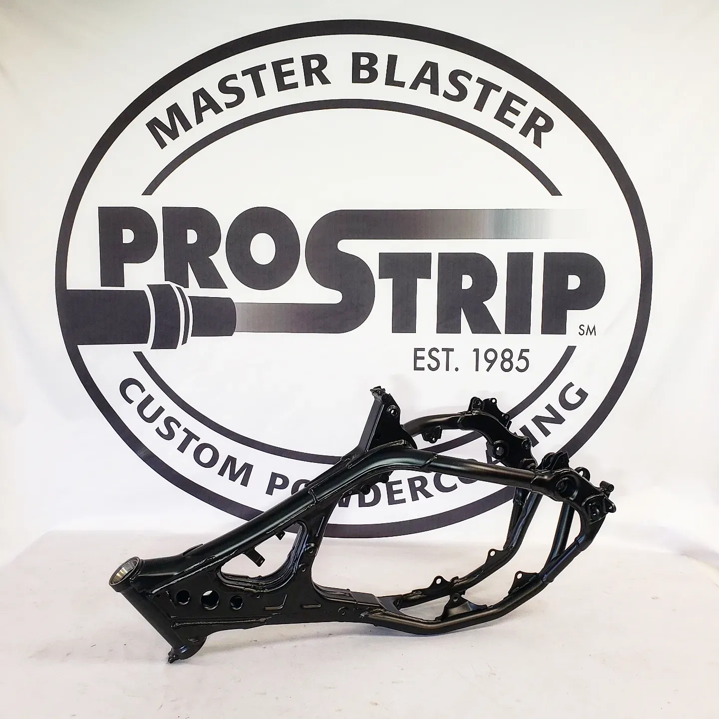 A motorcycle frame is sitting in front of a master blaster logo