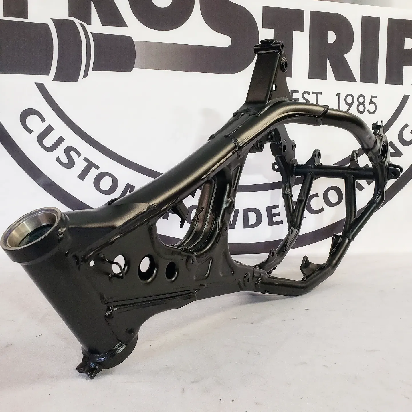 A motorcycle frame is sitting in front of a sign that says custom