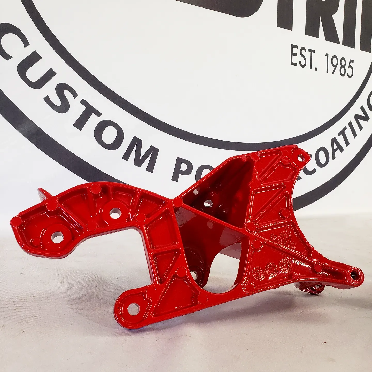 A red piece of metal is sitting in front of a custom coating logo