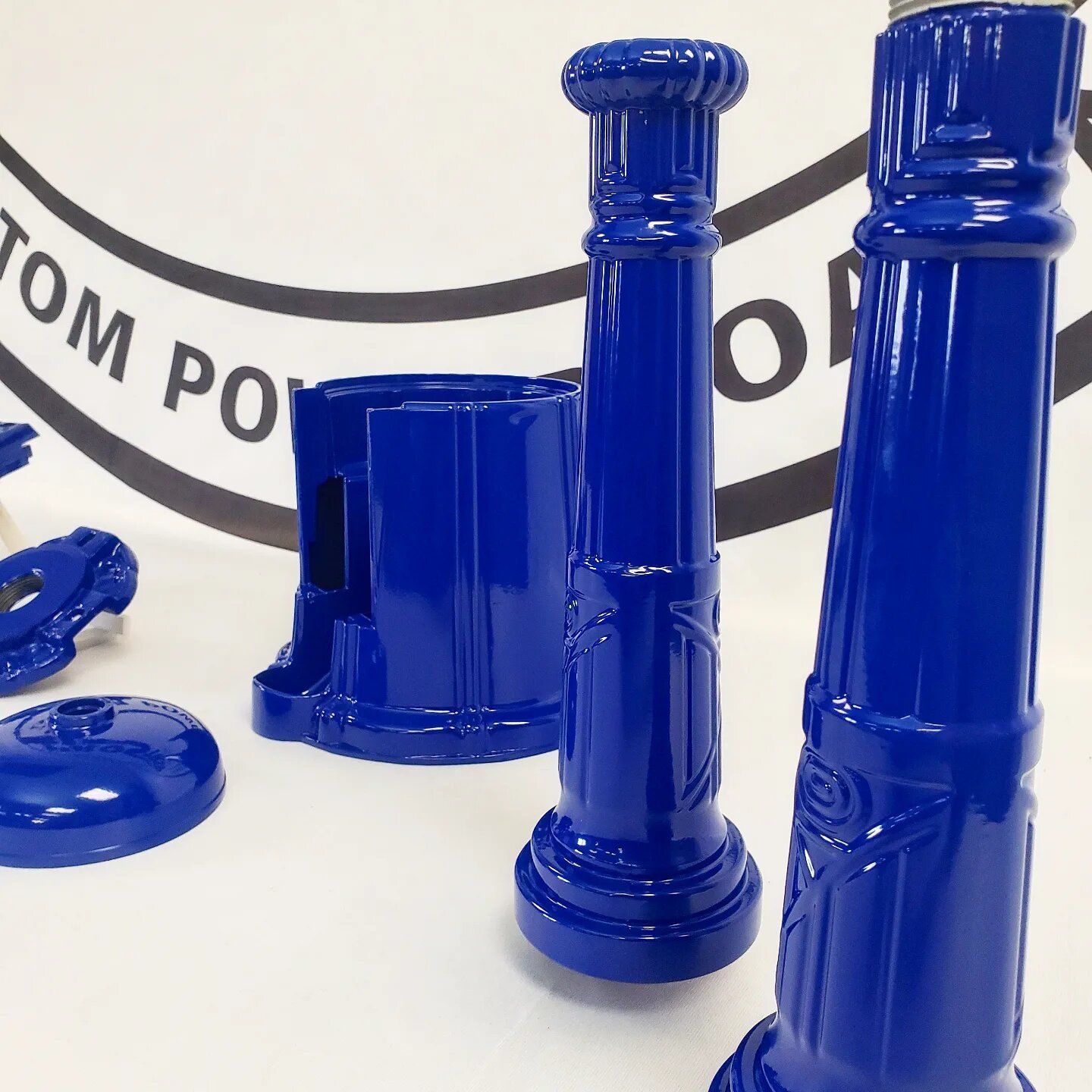 A group of blue pillars are sitting on a table in front of a sign that says custom poles