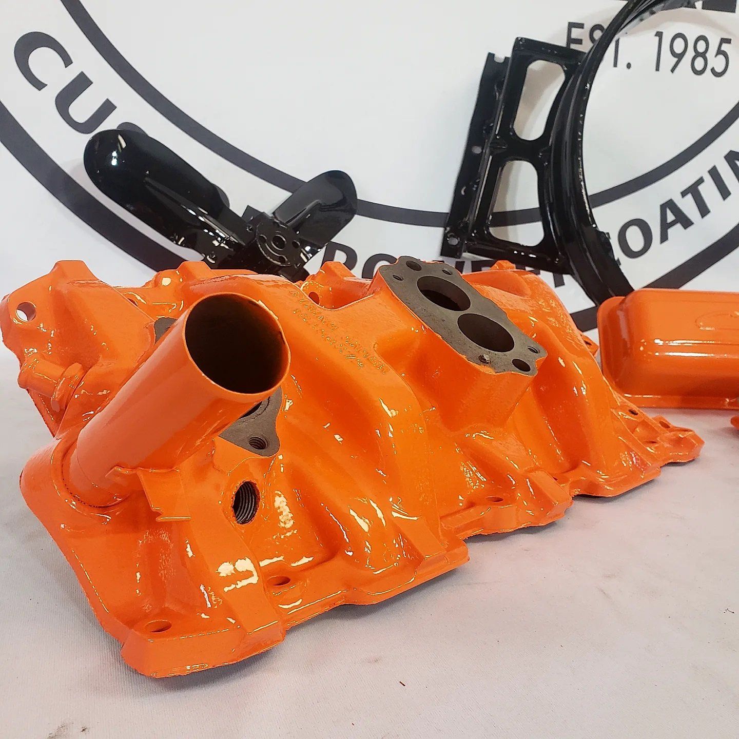 A close up of an orange intake manifold on a table
