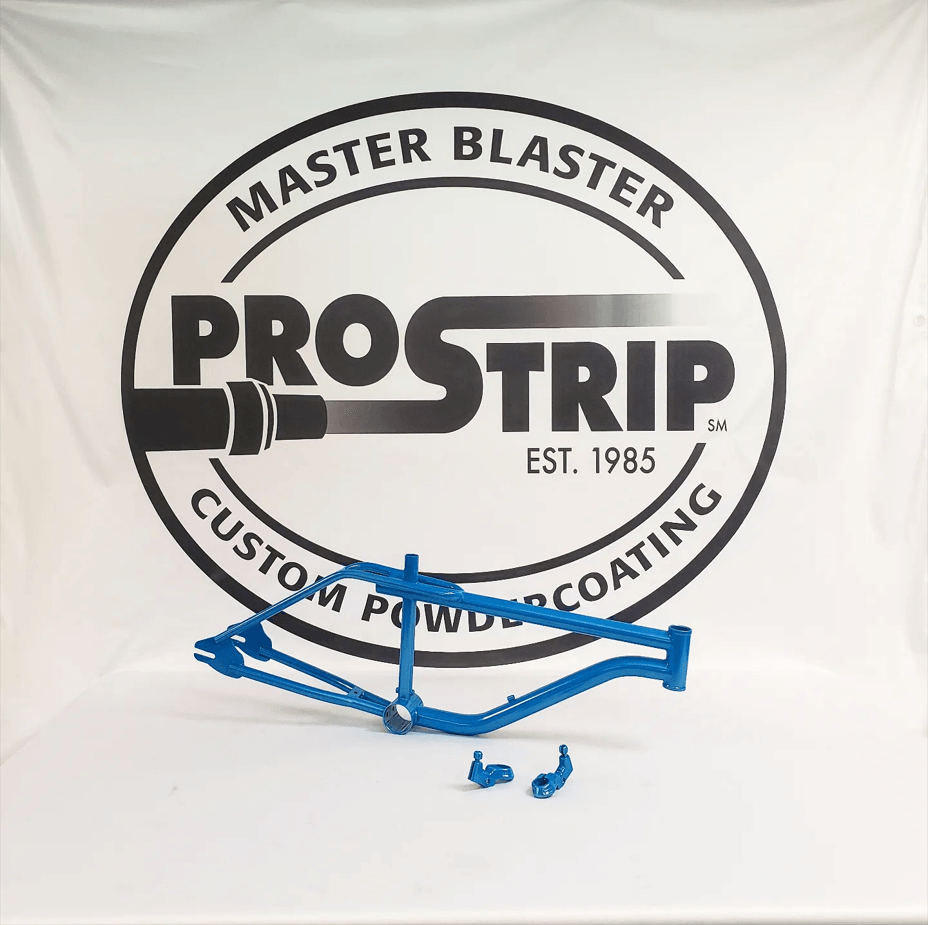 A blue bicycle frame is sitting in front of a master blaster prostrip logo