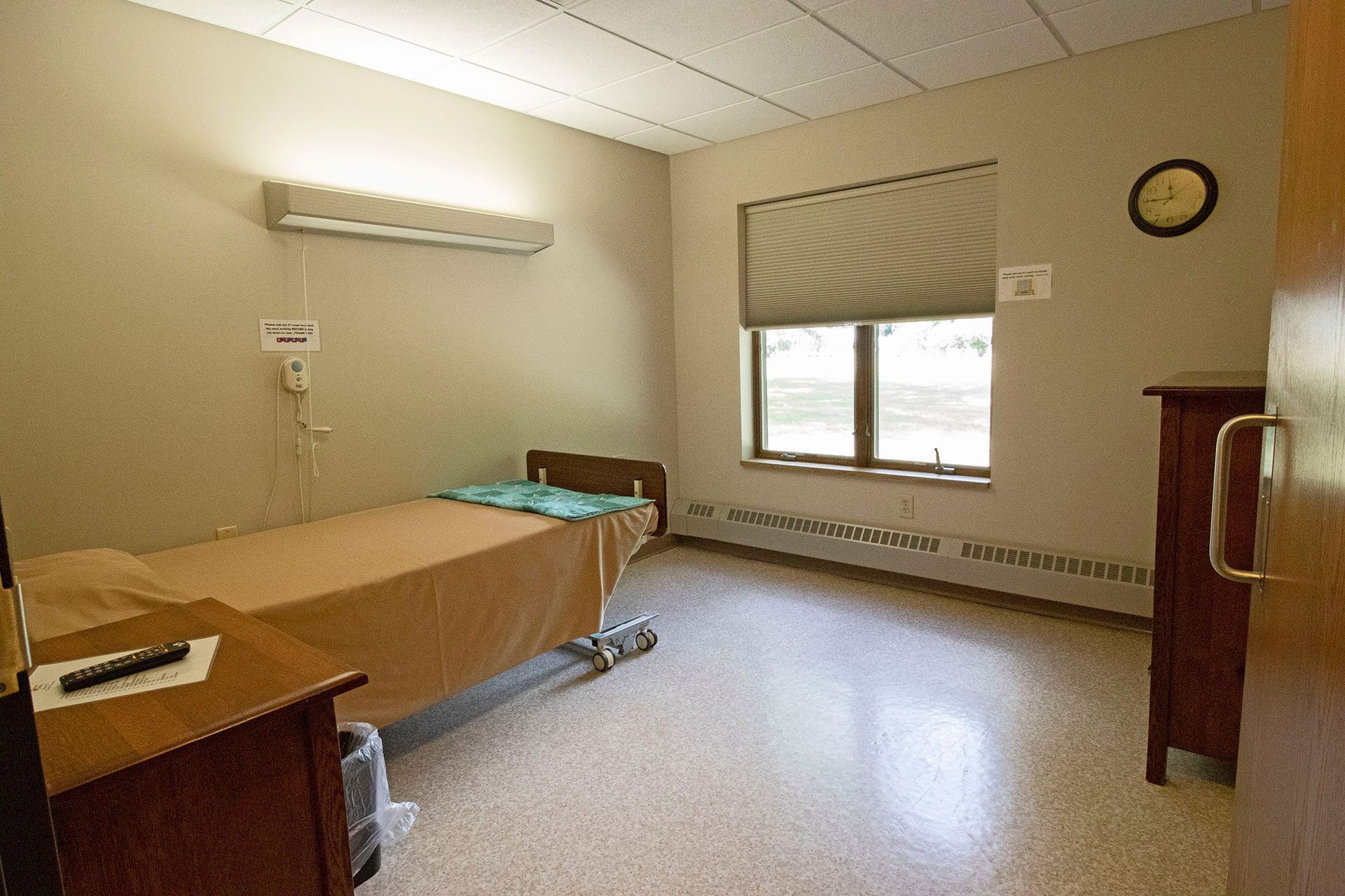 A hospital room with a bed and a clock on the wall.