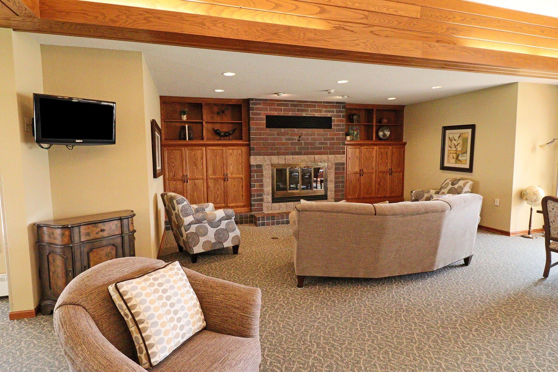 A living room with a couch , chair , television and fireplace.