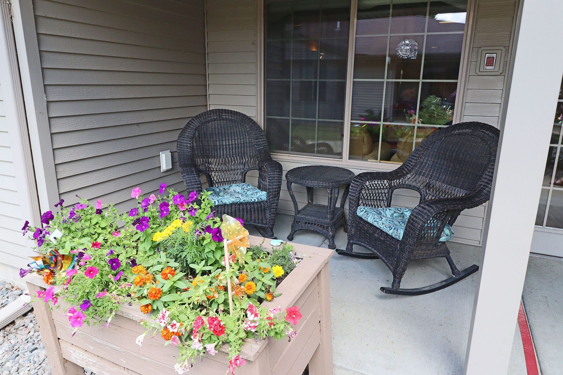 A porch with rocking chairs and a table with flowers in it
