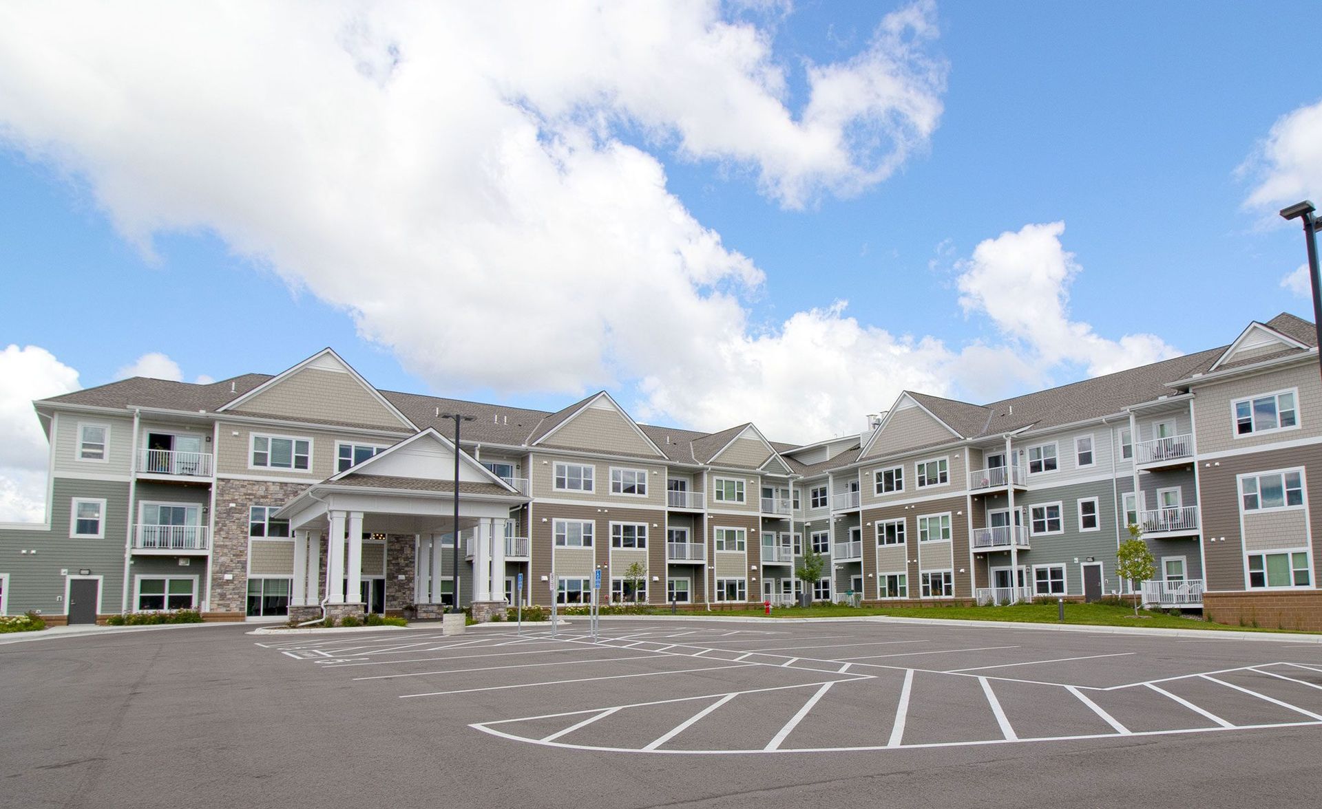 A large apartment building with a parking lot in front of it A large apartment building with a parking lot in front of it