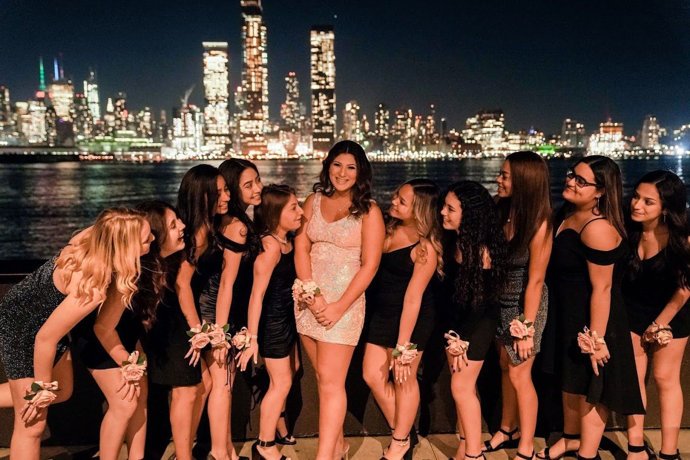 A group of women are posing for a picture in front of a city skyline at night.