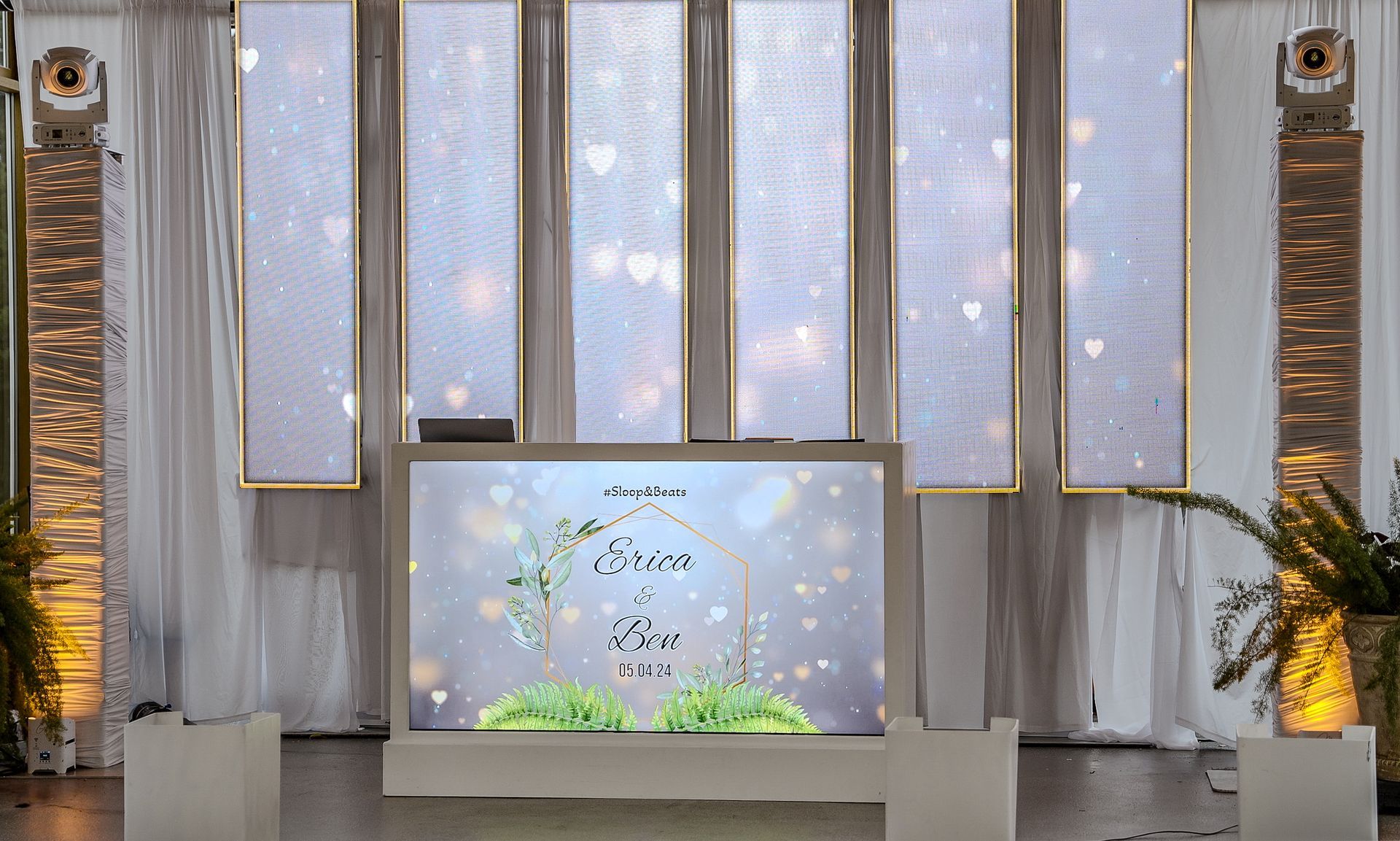 A dj booth is sitting in front of a wall of windows.