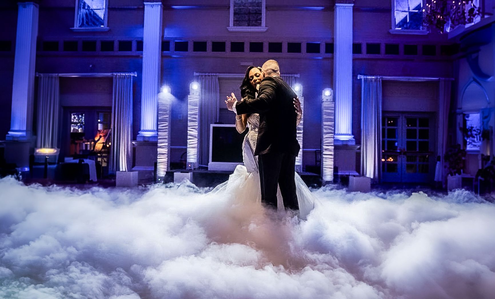A bride and groom are dancing in the clouds at their wedding reception.