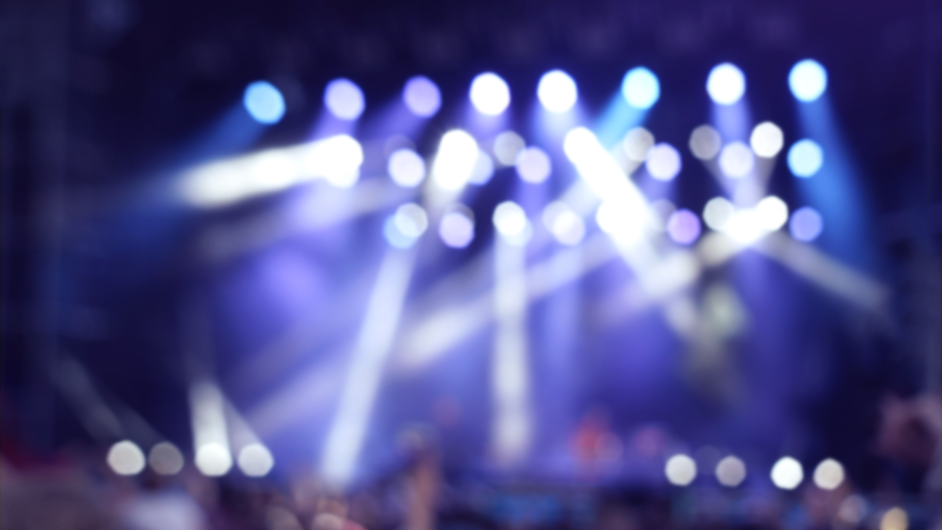 A blurry picture of a crowd at a concert with purple lights.