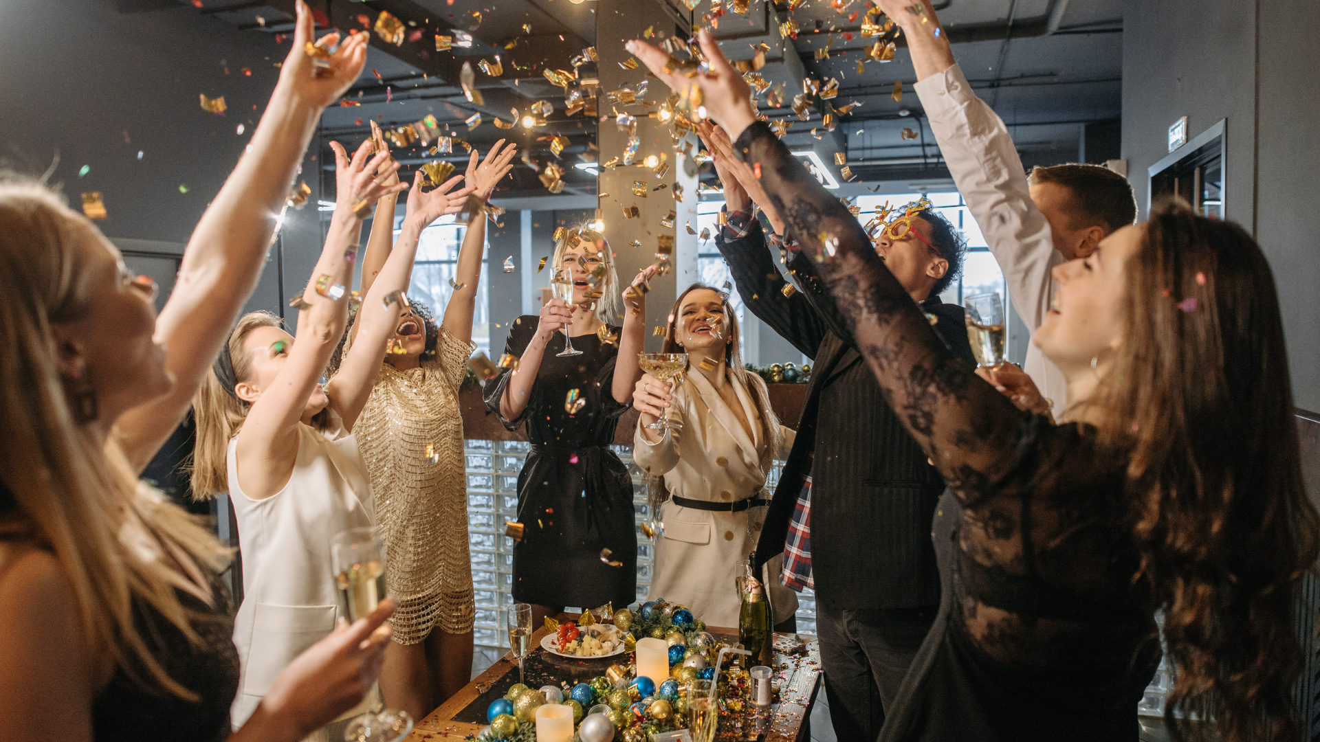 A group of people are throwing confetti in the air at a party.