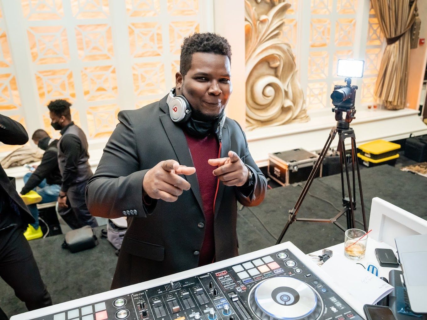 A man in a suit is standing in front of a dj mixer.
