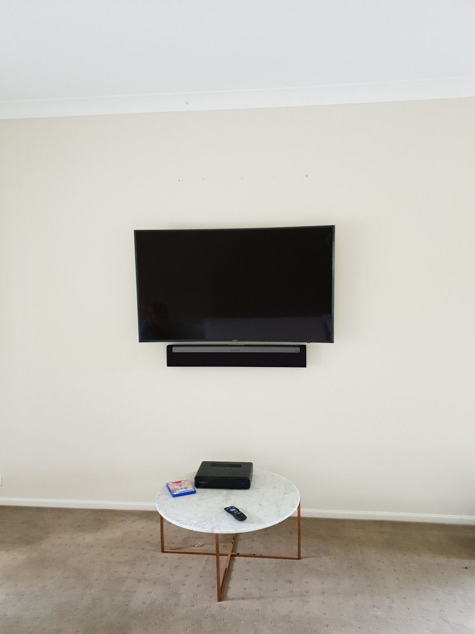 A living room with a flat screen TV mounted to the wall and a coffee table.