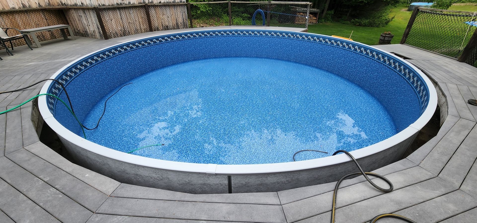 A round swimming pool is sitting on top of a wooden deck.