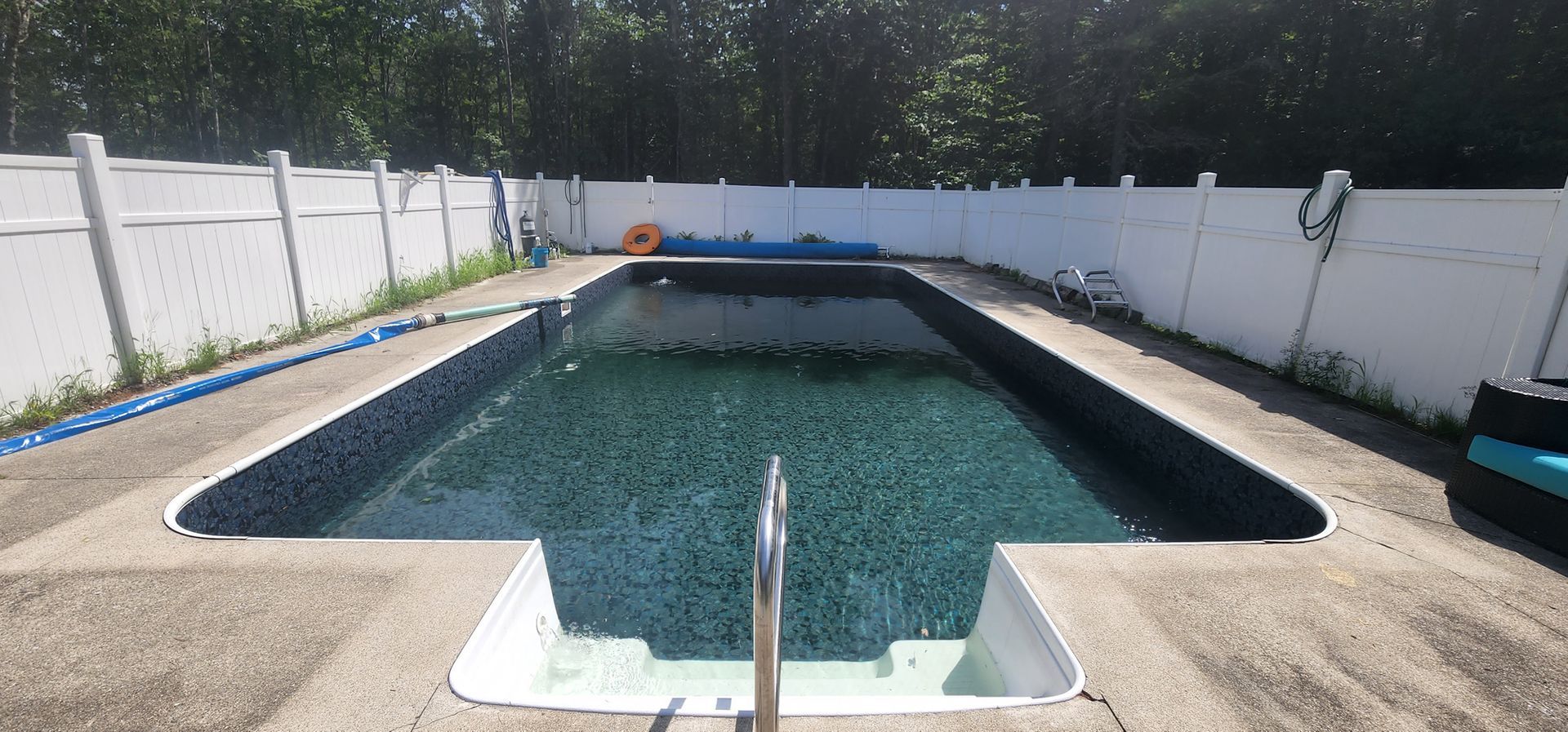 A large swimming pool with a white fence surrounding it