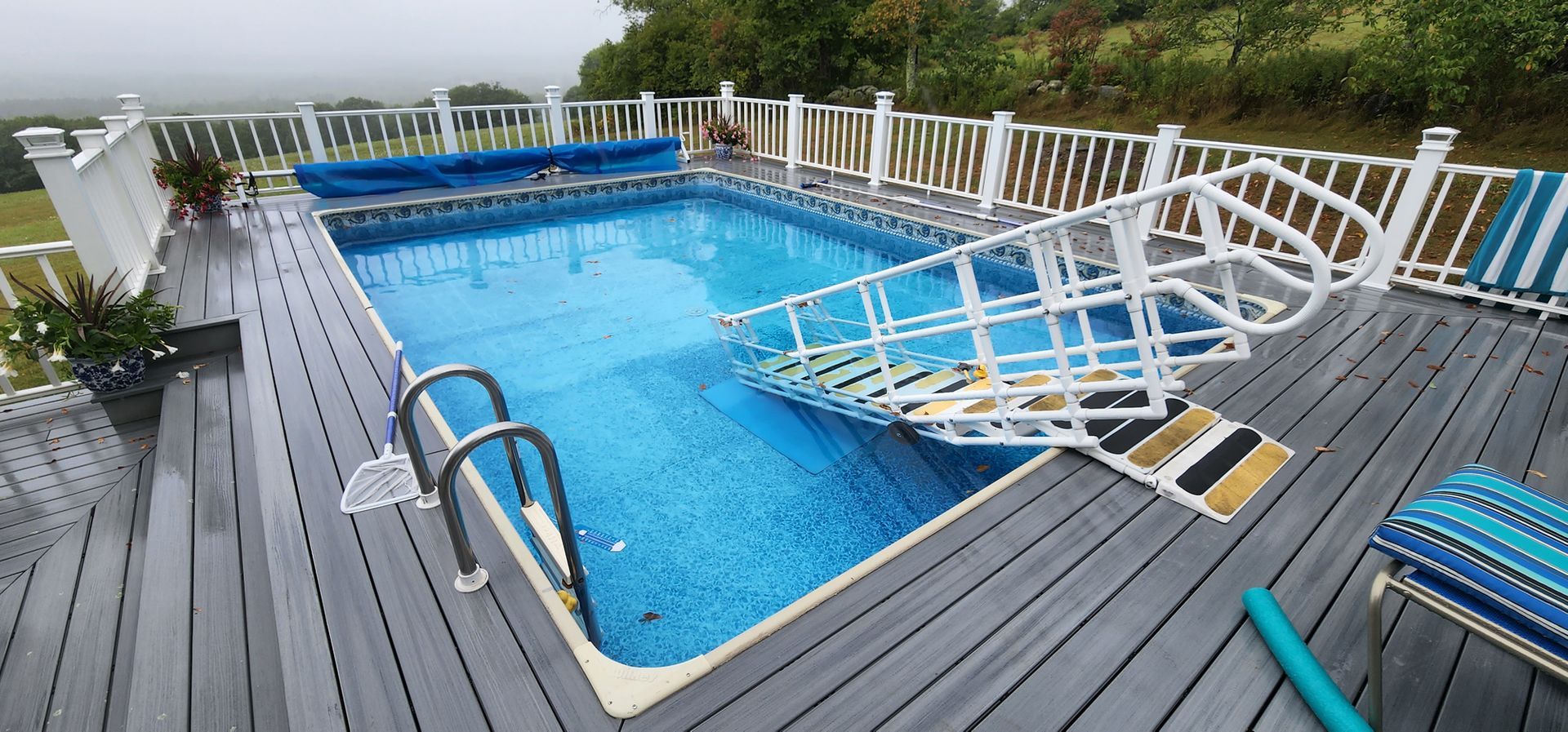 A large swimming pool is sitting on top of a wooden deck.