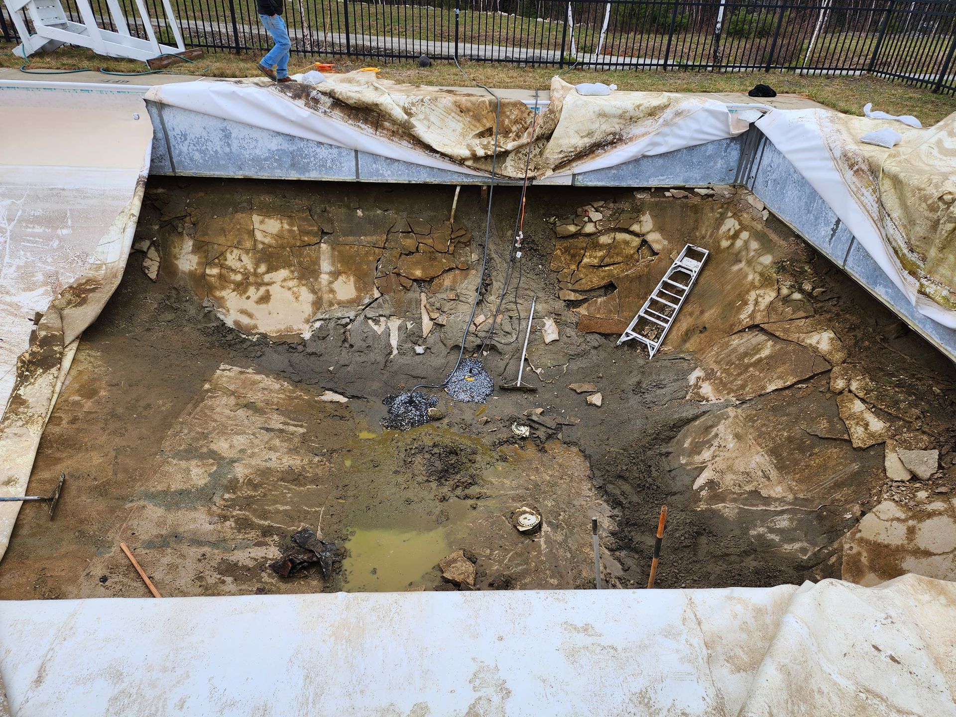 A ladder is sitting in the middle of a muddy pool.