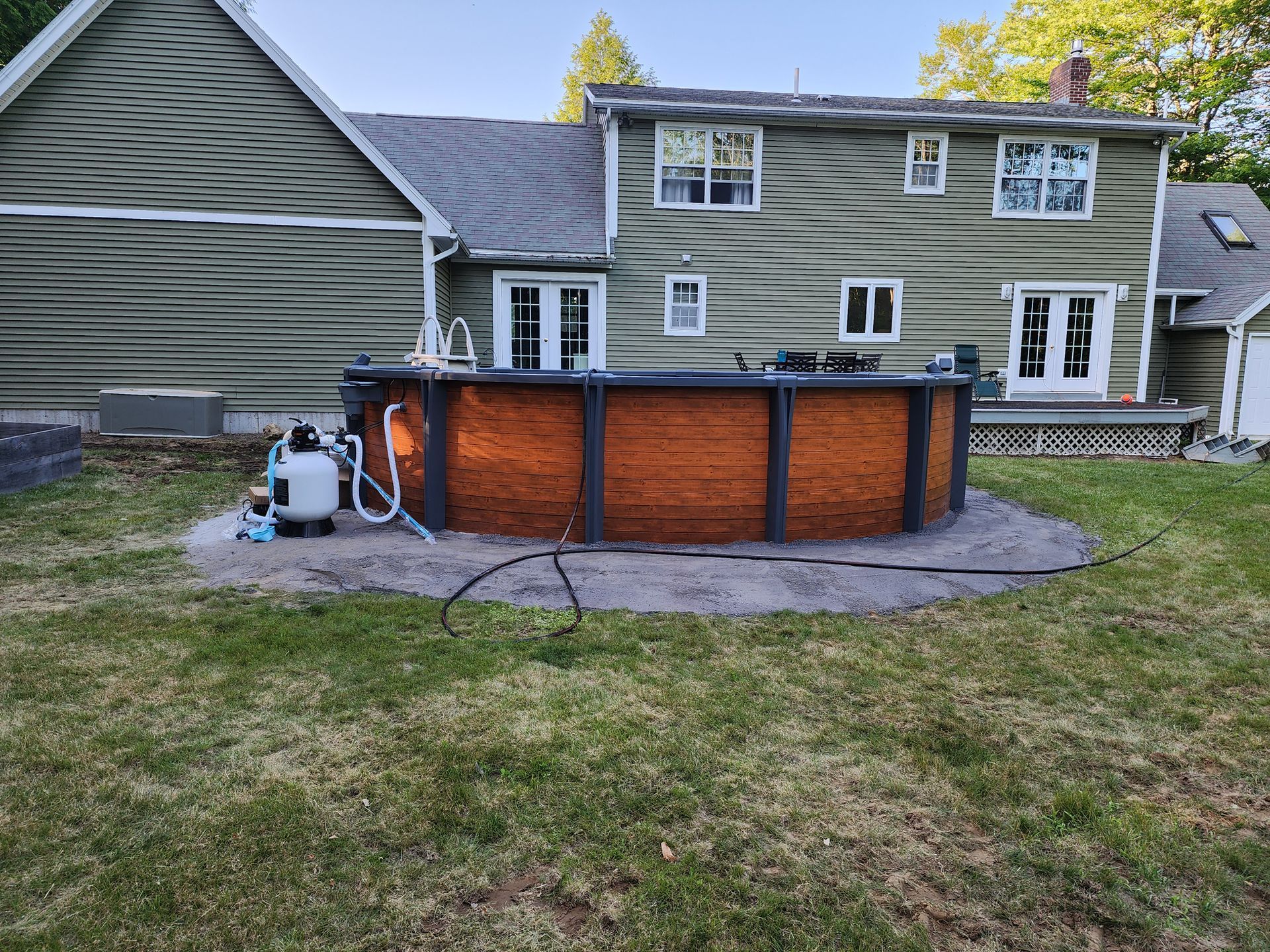A large swimming pool is sitting in the backyard of a house.