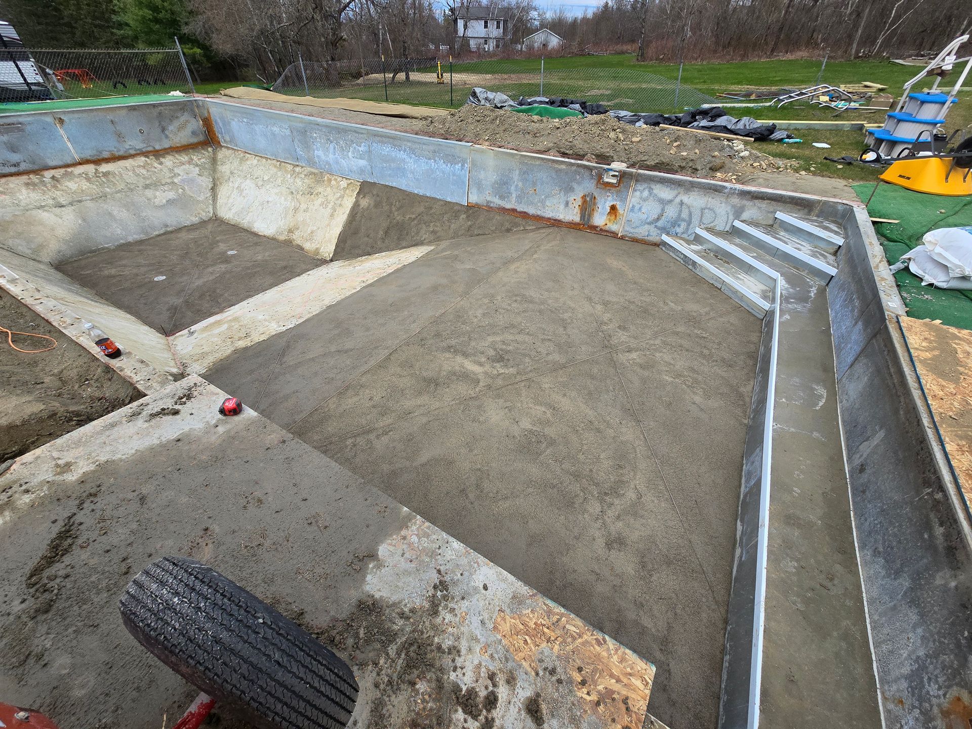 A concrete pool is being built in a backyard.