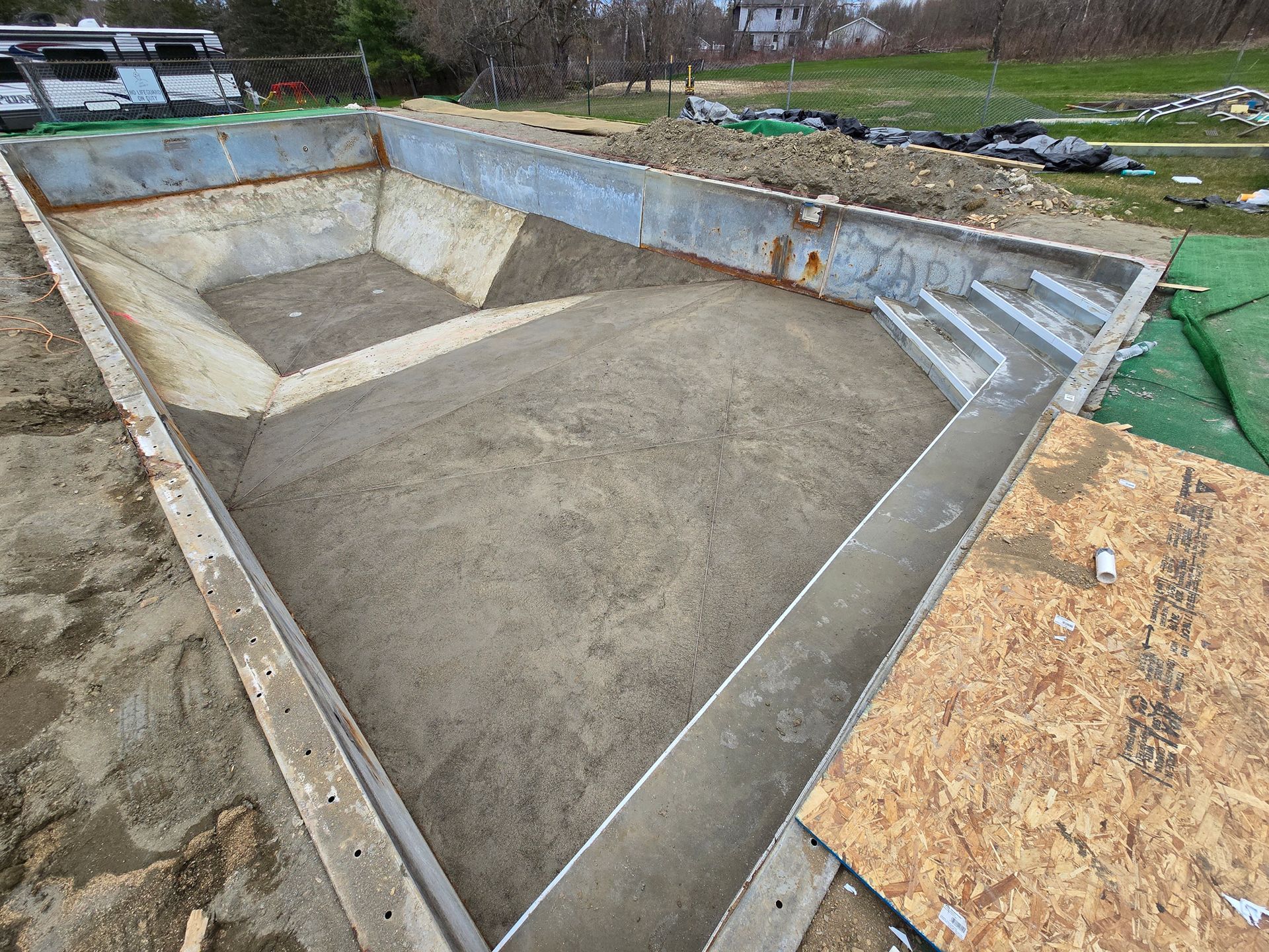 A concrete pool is being built in a backyard.