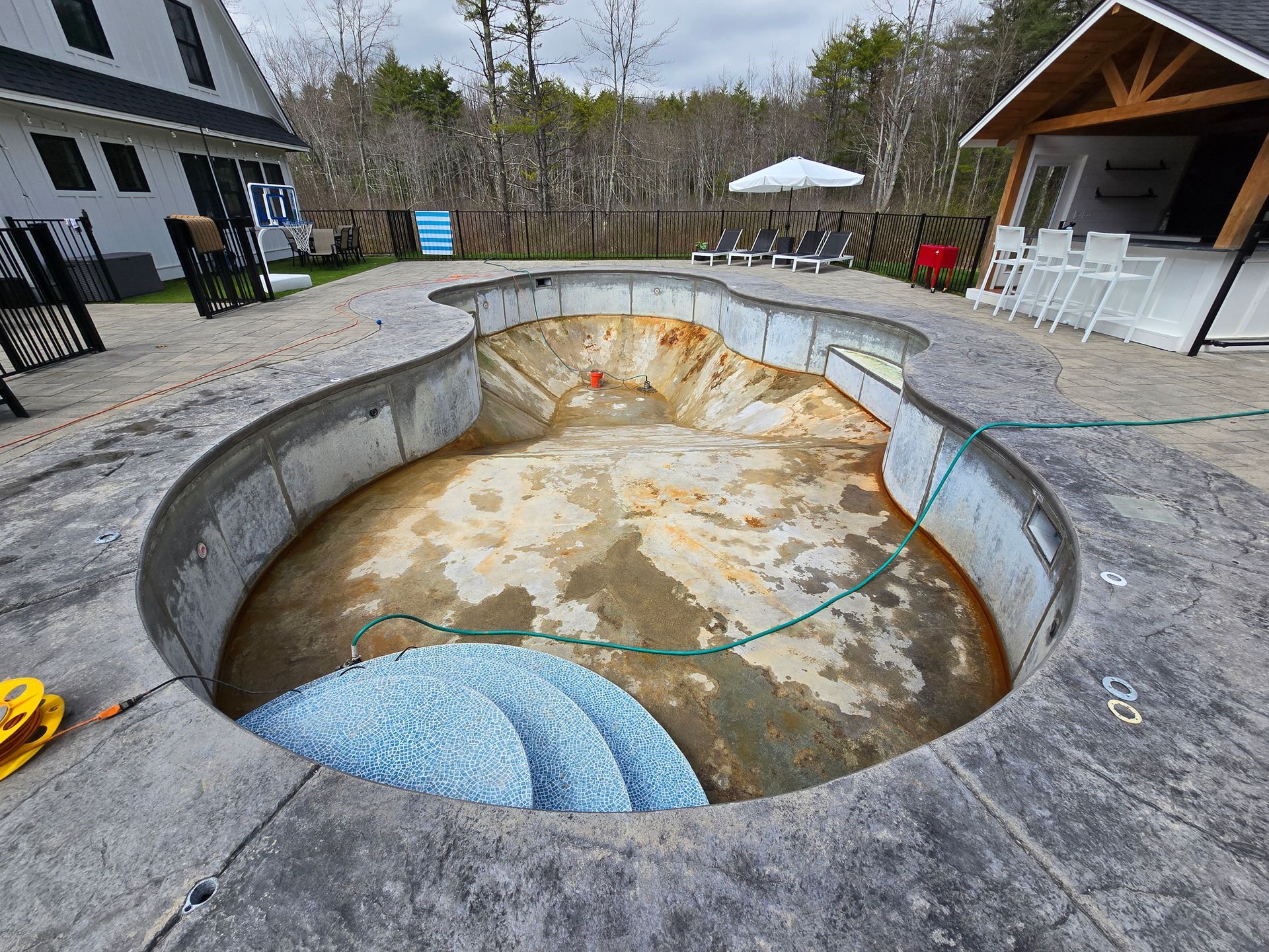 A swimming pool is being built in the backyard of a house.