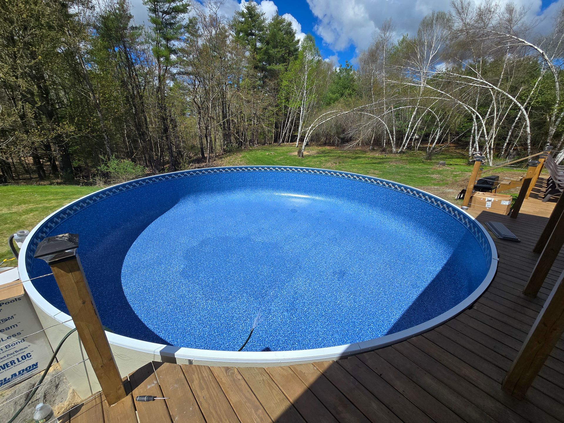 A round swimming pool is sitting on top of a wooden deck.