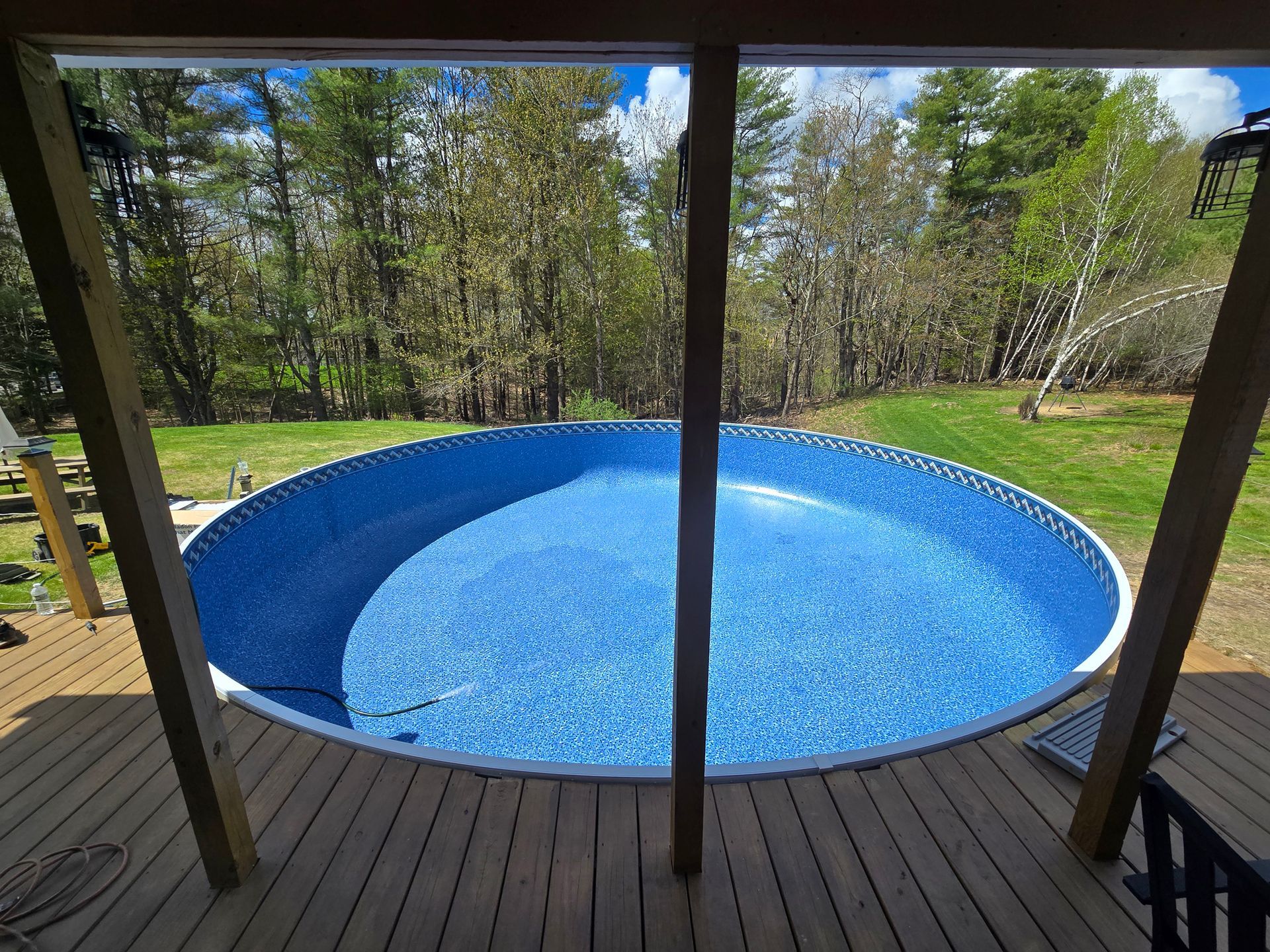 A round swimming pool is sitting on top of a wooden deck.