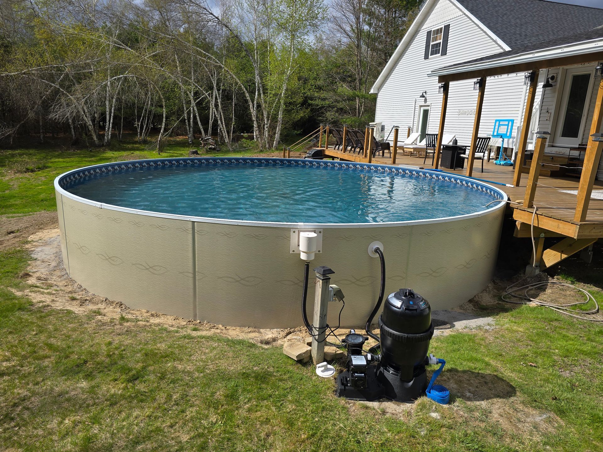 A large swimming pool is sitting in the grass in front of a house.