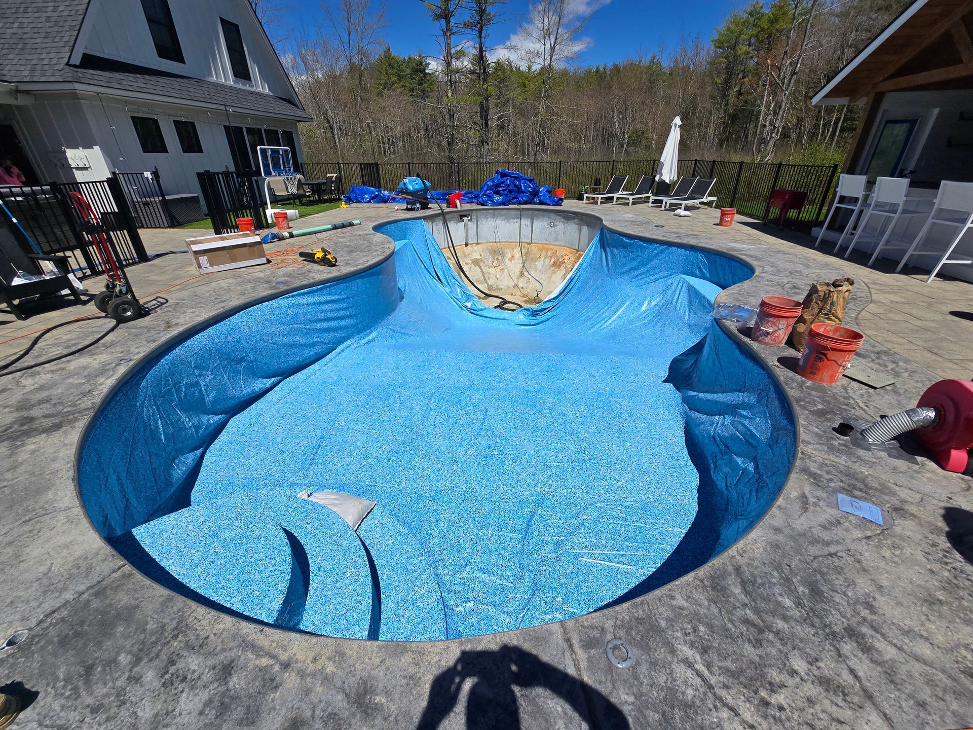 A large swimming pool is being built in the backyard of a house.