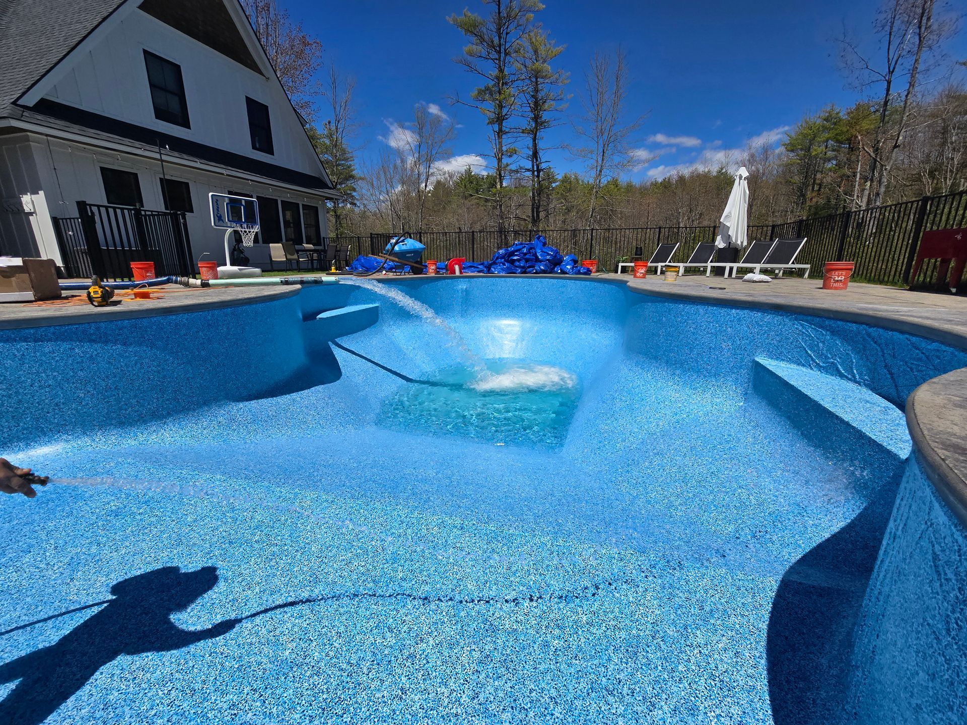 A person is cleaning a swimming pool with a hose.